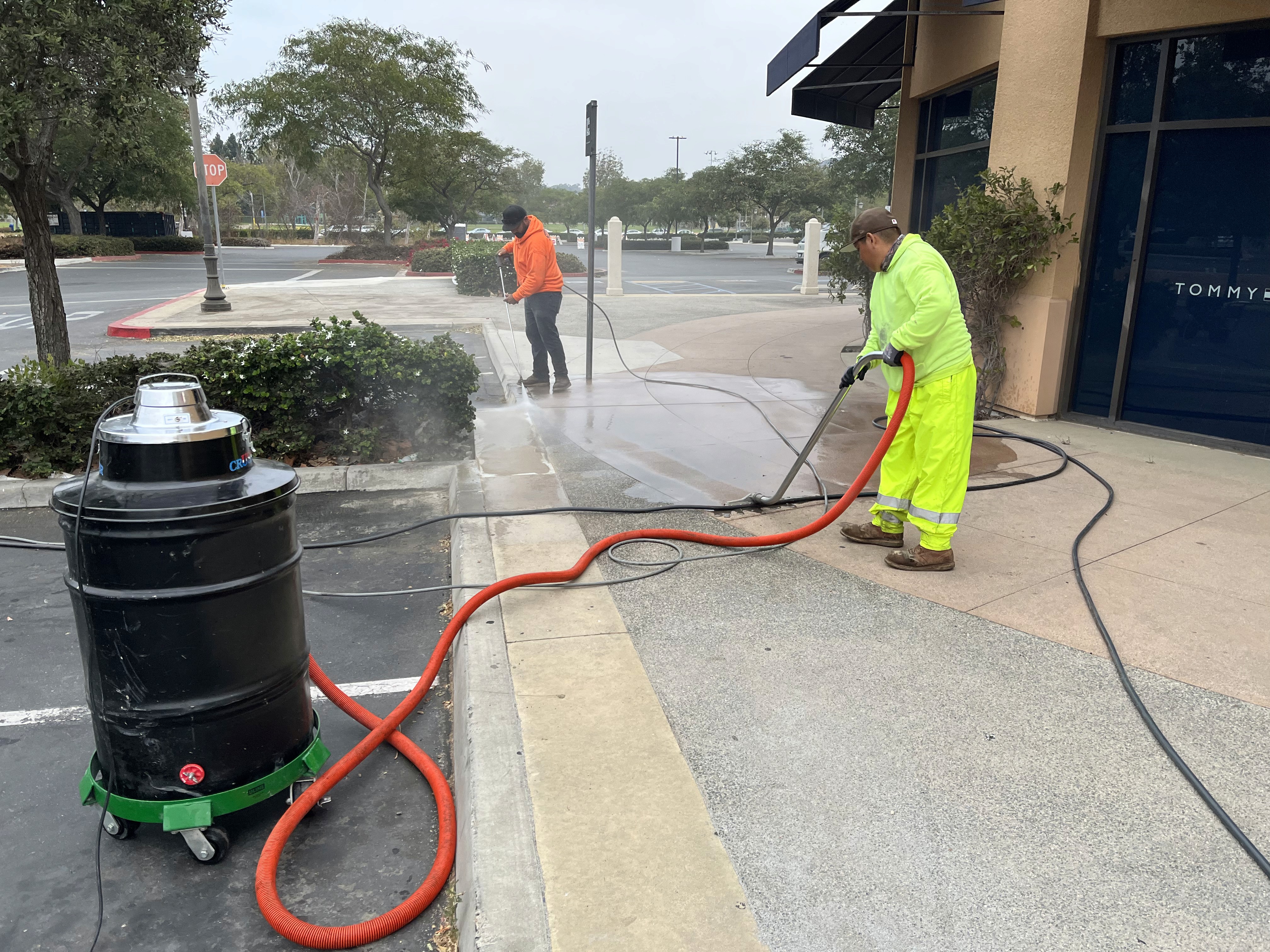 2 trabajadores limpiando concreto fresco frente a los escaparates del centro comercial