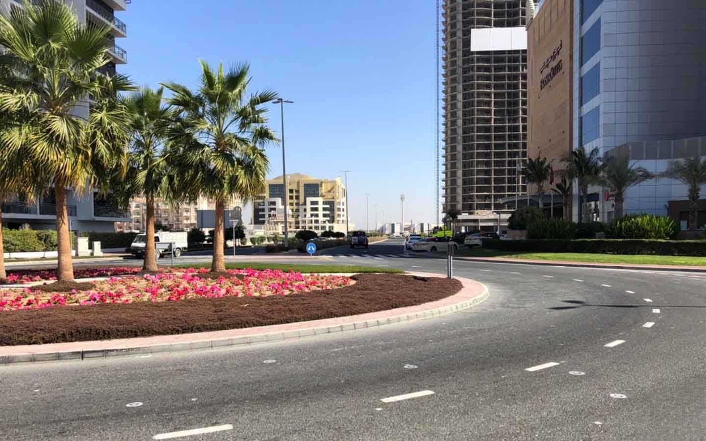 Wide street view of a prime real estate location in Dubai, featuring landscaped roundabouts and high-rises.