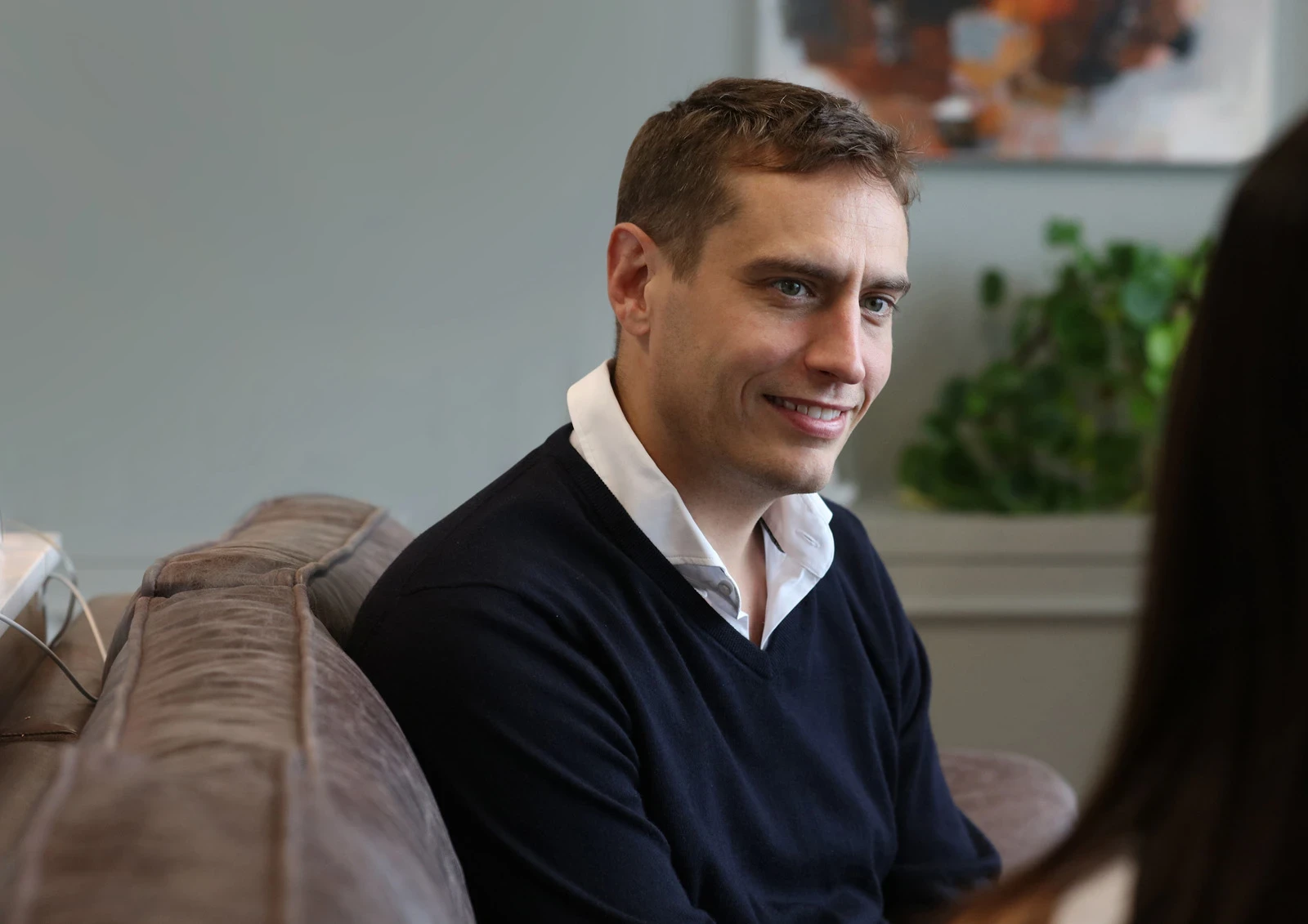 James Sutton, CEO smiling whilst sat down on a sofa