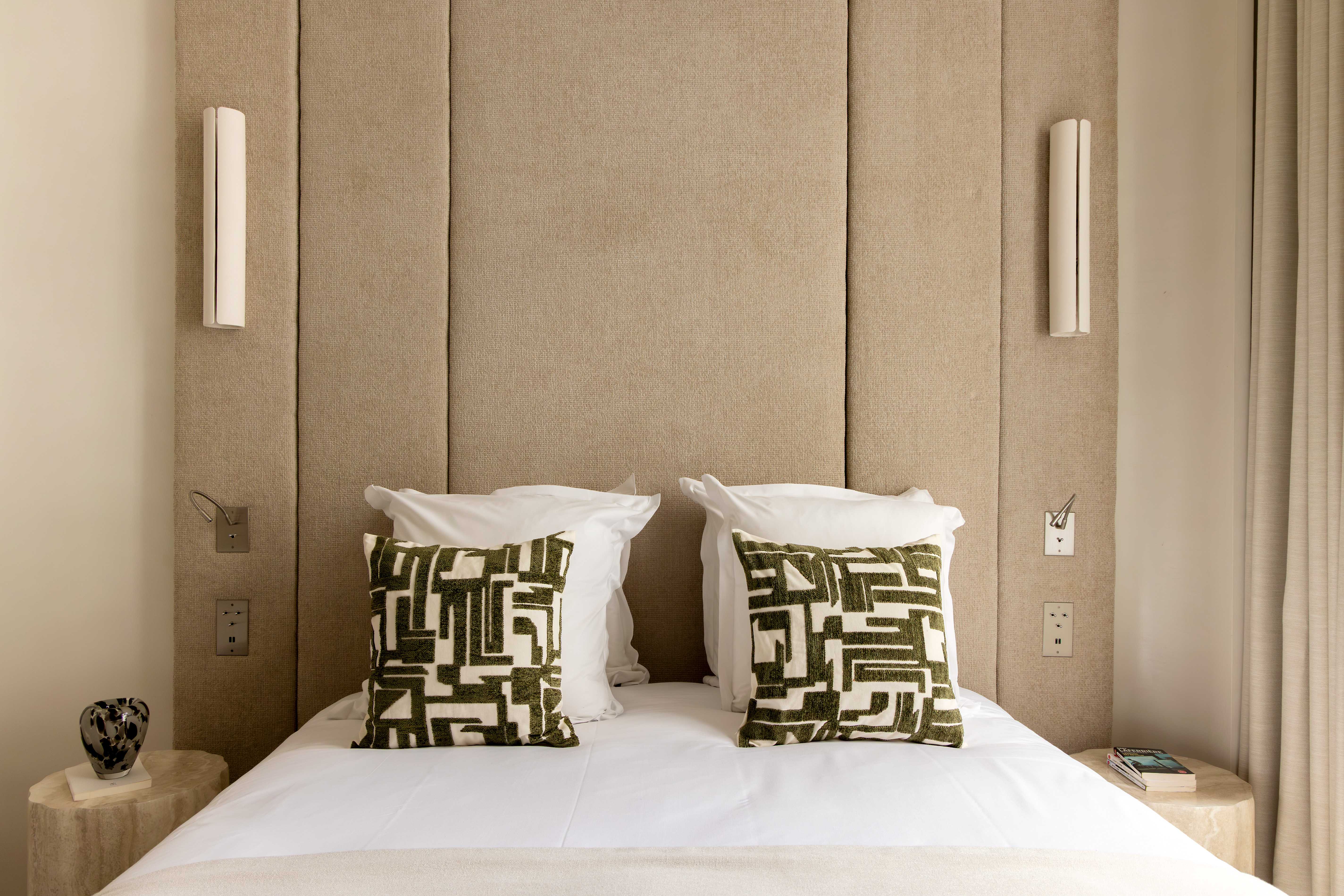 Lit double avec tete de lit sable en panneaux, coussins graphiques verts et chevets en bois naturel