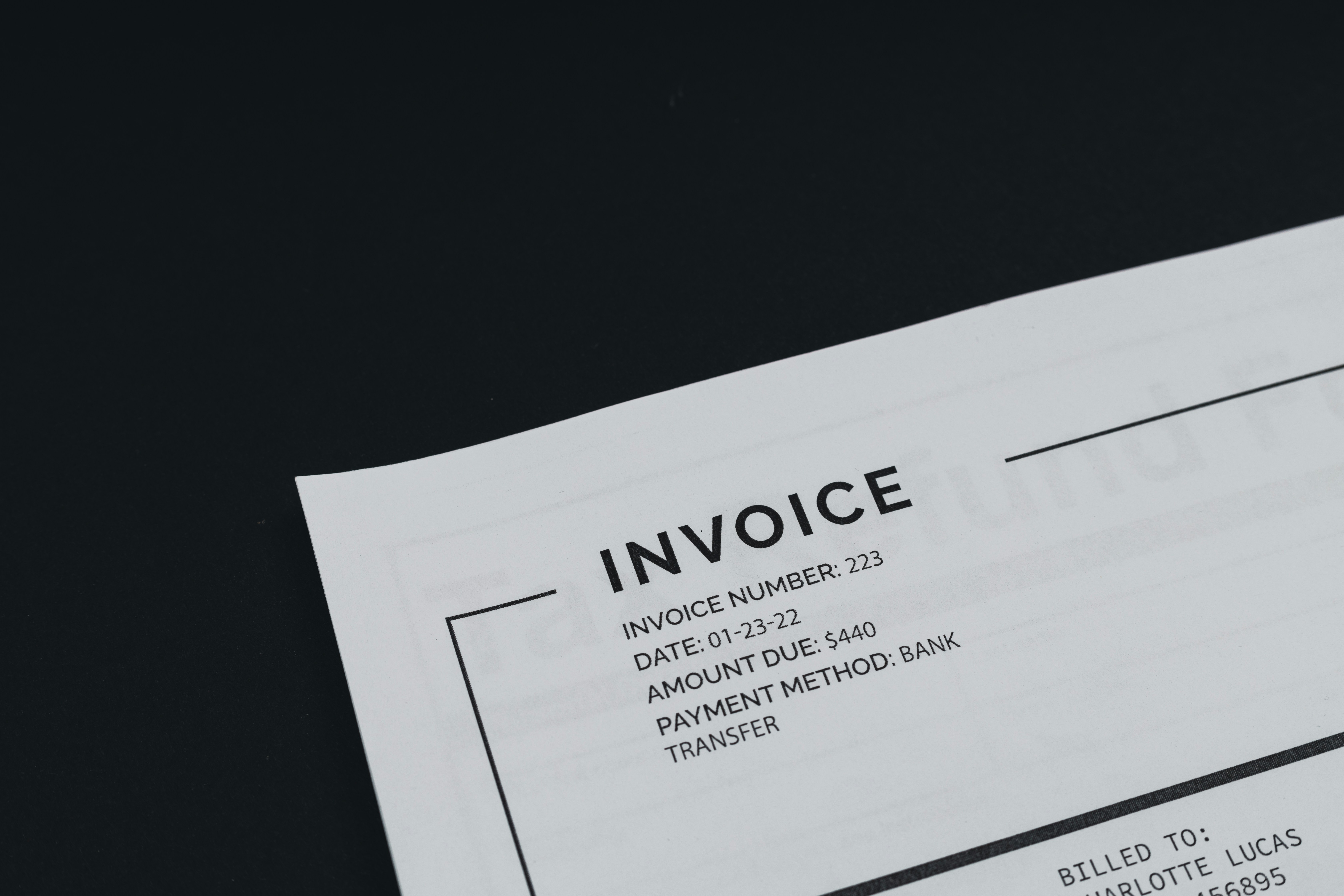 Close-up of a small business invoice showing invoice number, date, amount due of $440, and bank transfer payment method, on a black background.
