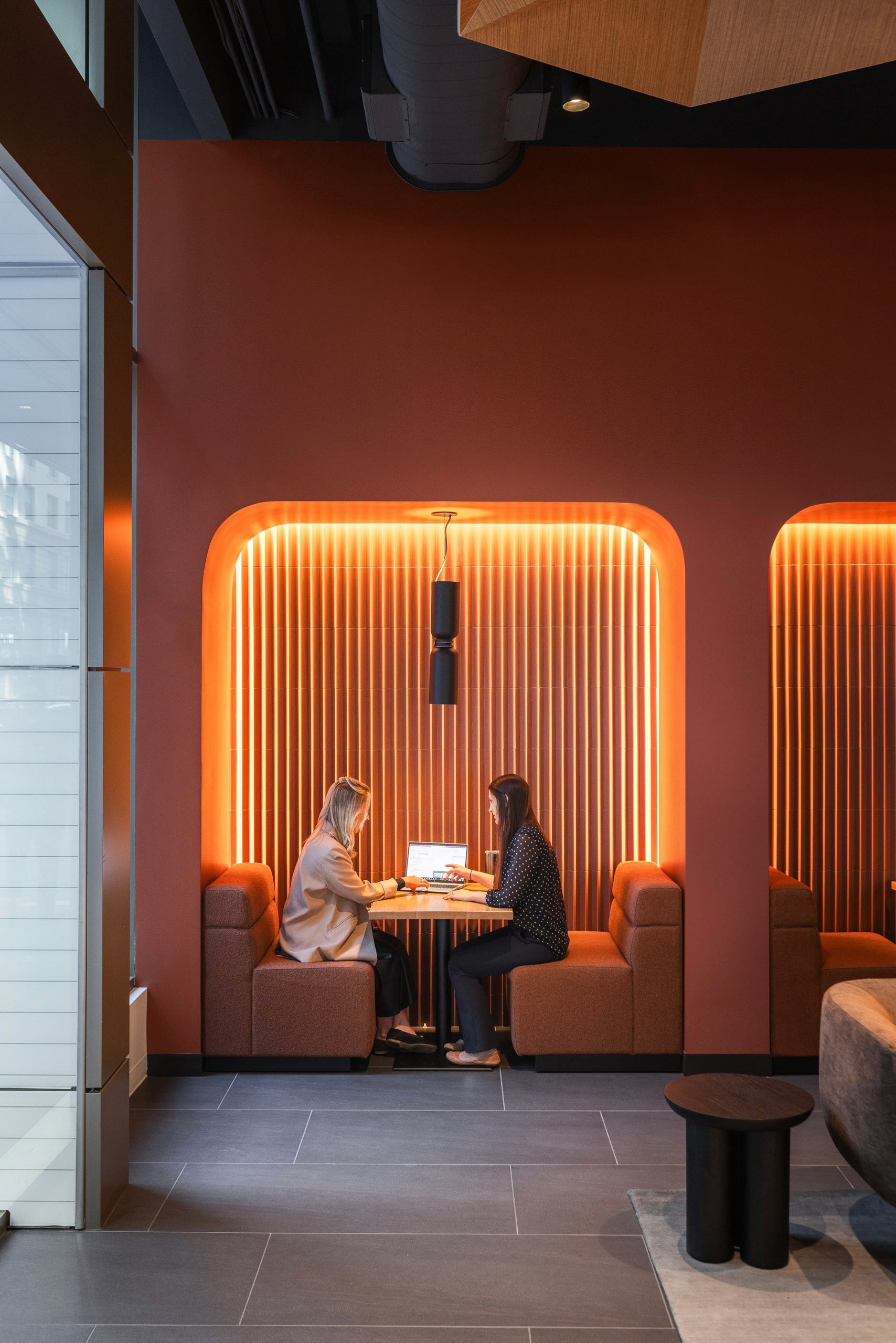Two people work on a laptop in a modern alcove.