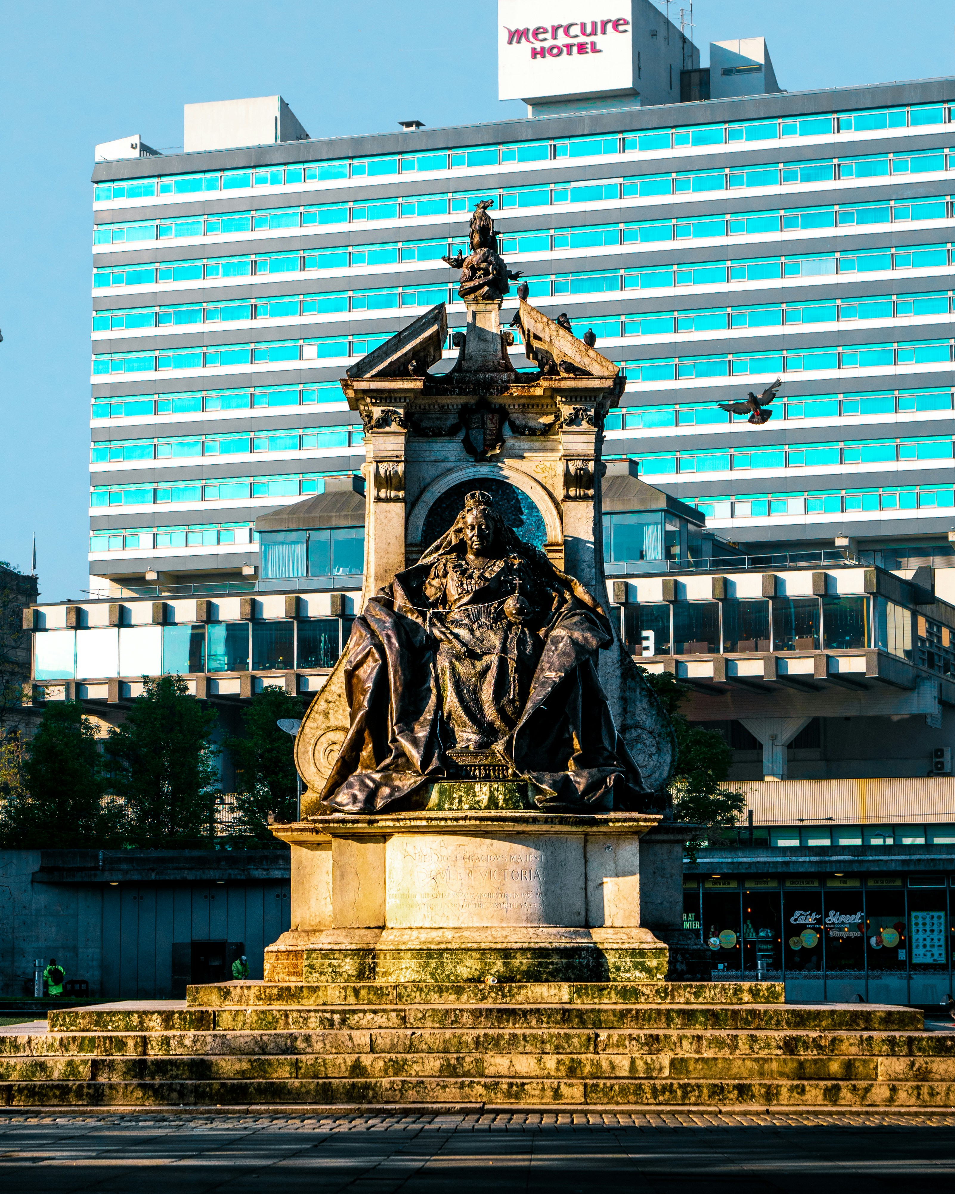 statue of man holding book near building during daytime