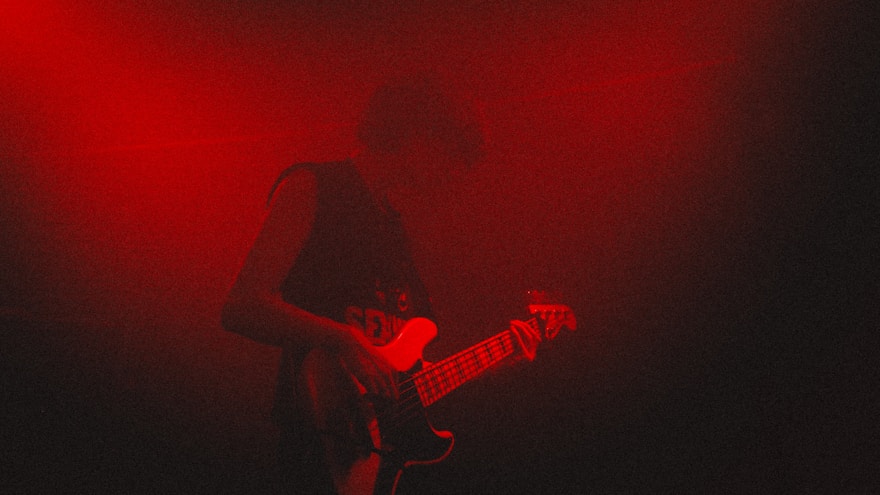 Red lit guitarist performing live on stage