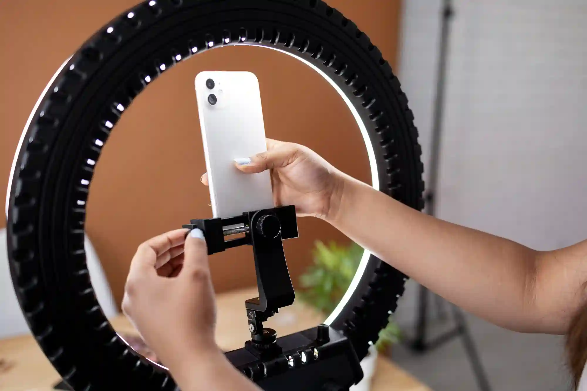 A person adjusts a phone on a ring light stand.