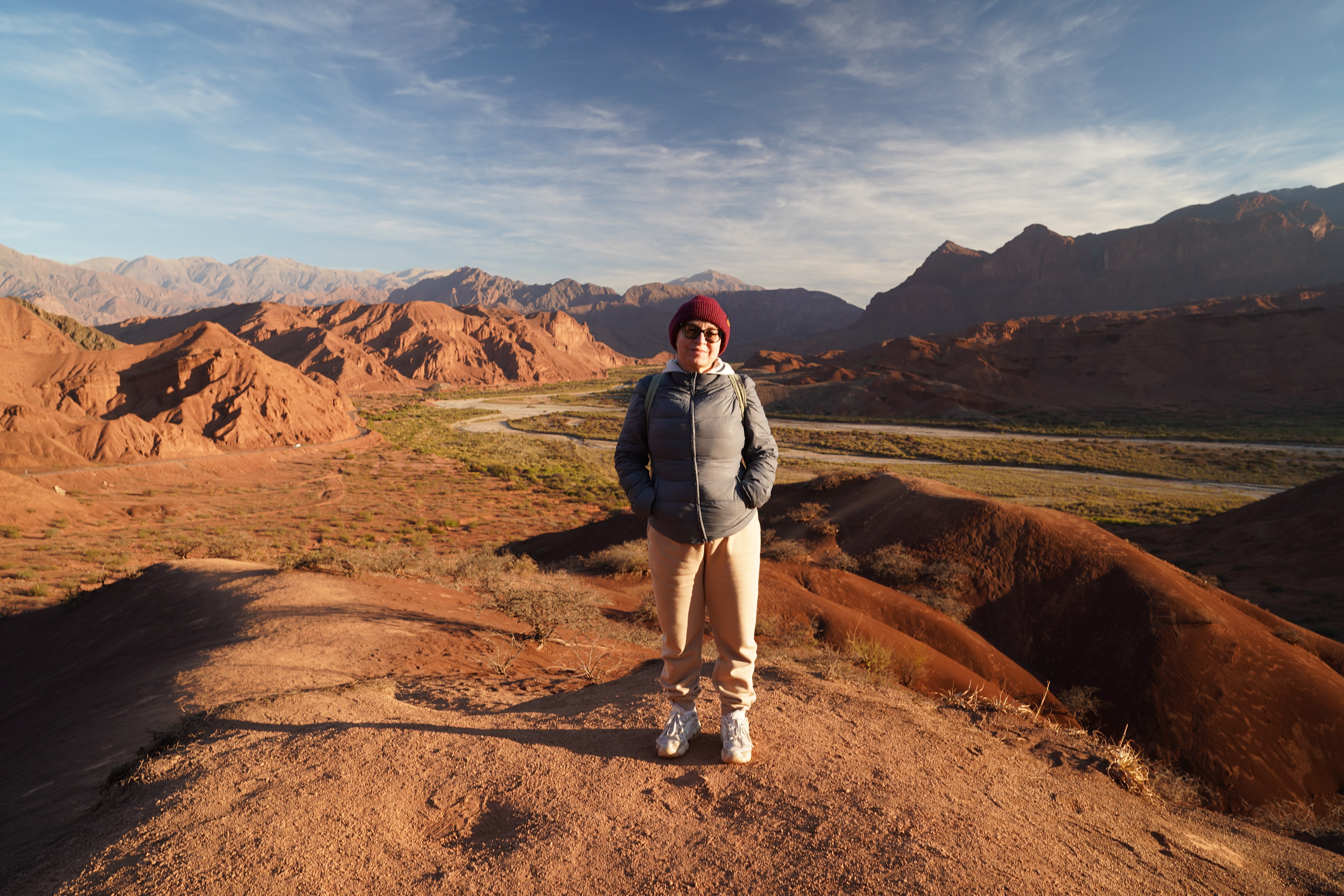 Svetlana Gabitova de pie en un paisaje montañoso de tonos rojizos en el norte argentino, representando el hogar y el proyecto de vida que construyó en el país.