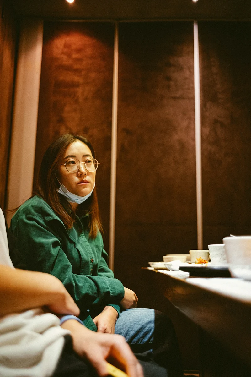 A woman talking with someone across a cafe table.