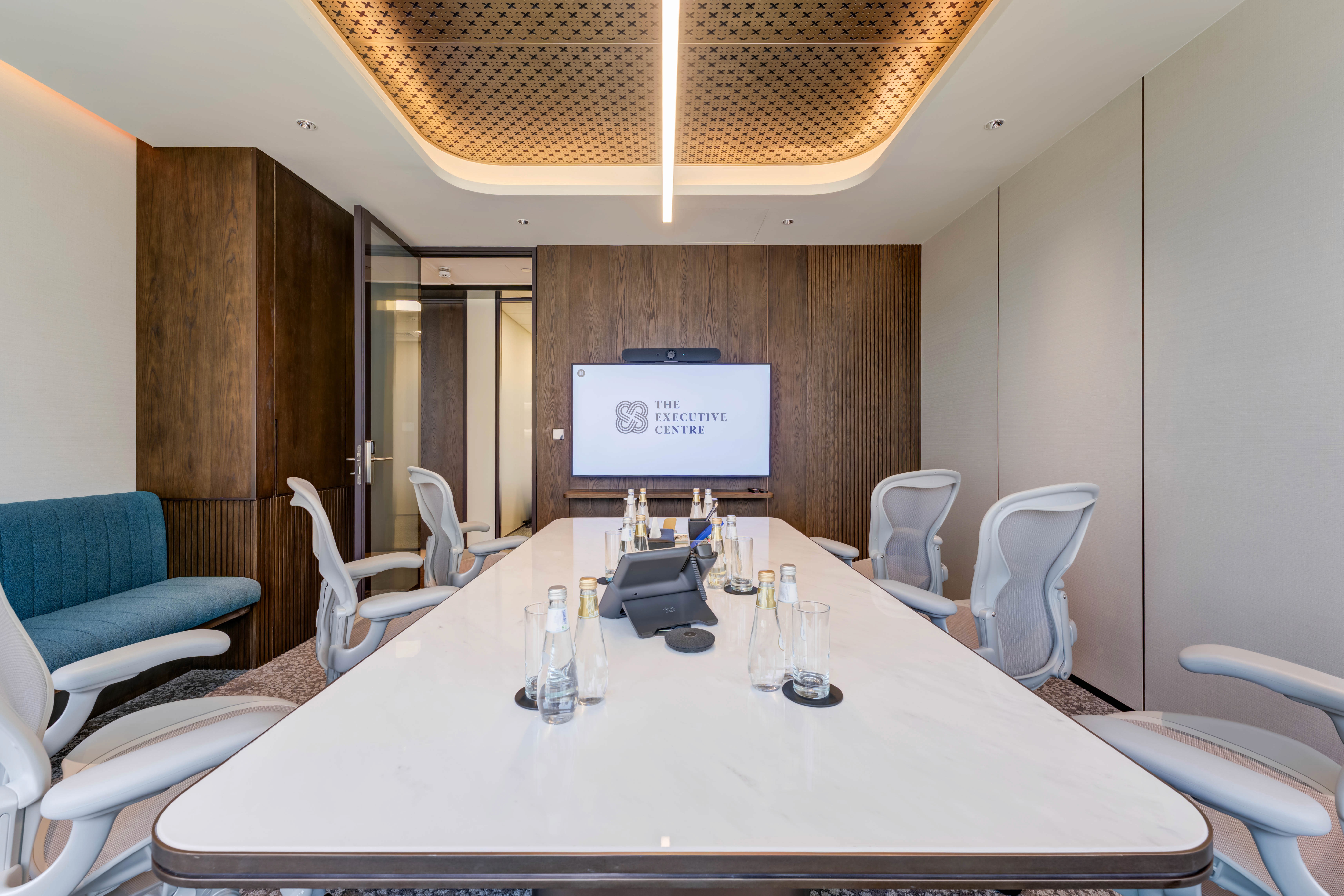Professional meeting room with a long white table, executive chairs, and an integrated display.