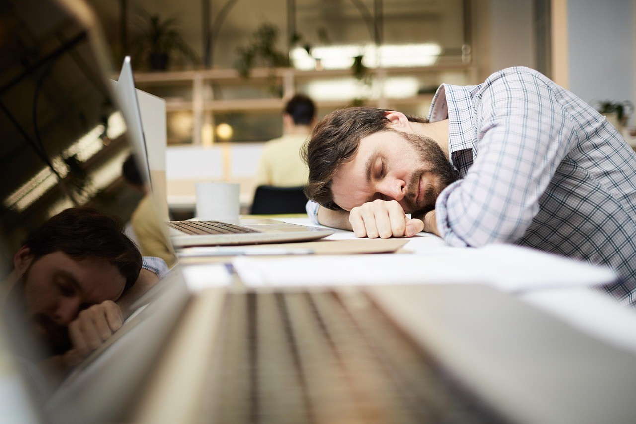 Exhausted person sleeping on laptop at desk