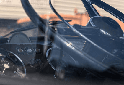 Close-up view of a classic truck dashboard and steering wheel through the windshield.
