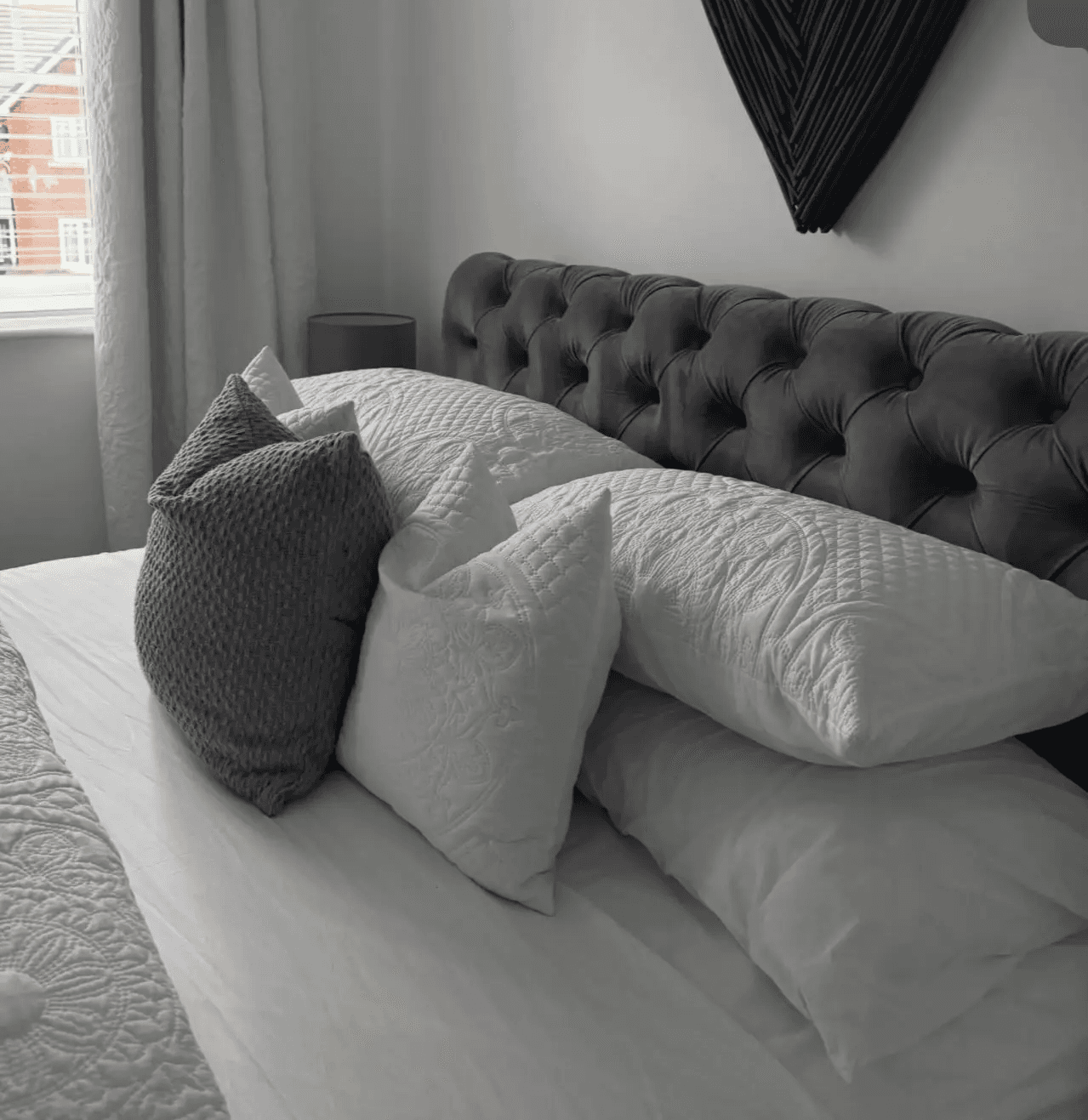 A professionally made bed with crisp white linens and perfectly arranged pillows, showcasing the fresh bed sheet and linen refresh add-on service.
