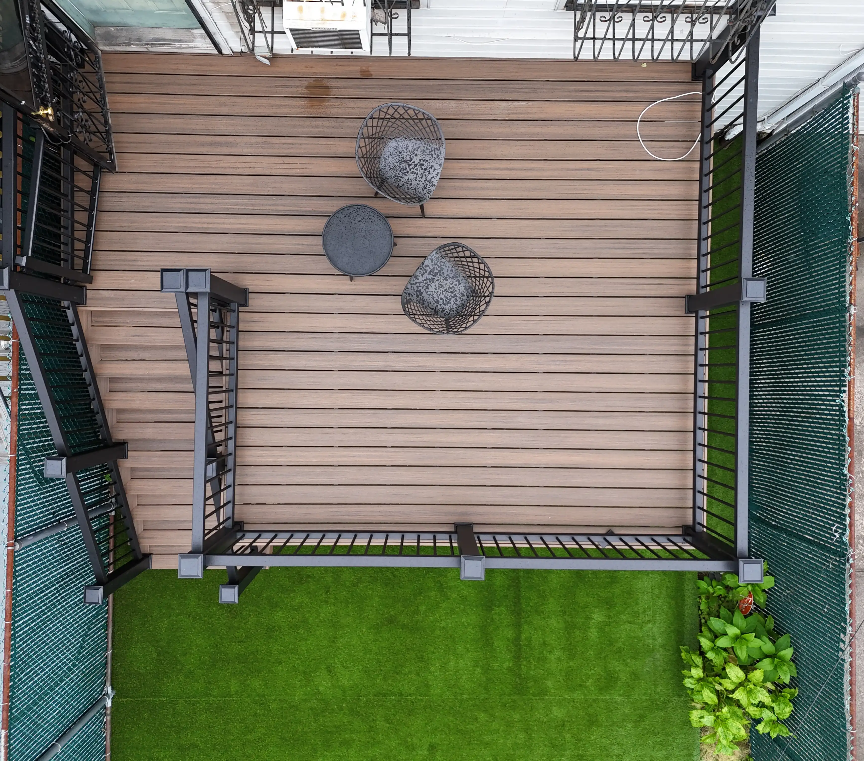 Aerial shot of a residential backyard deck design with durable brown composite decking and black aluminum railings in Bed-Stuy, Brooklyn