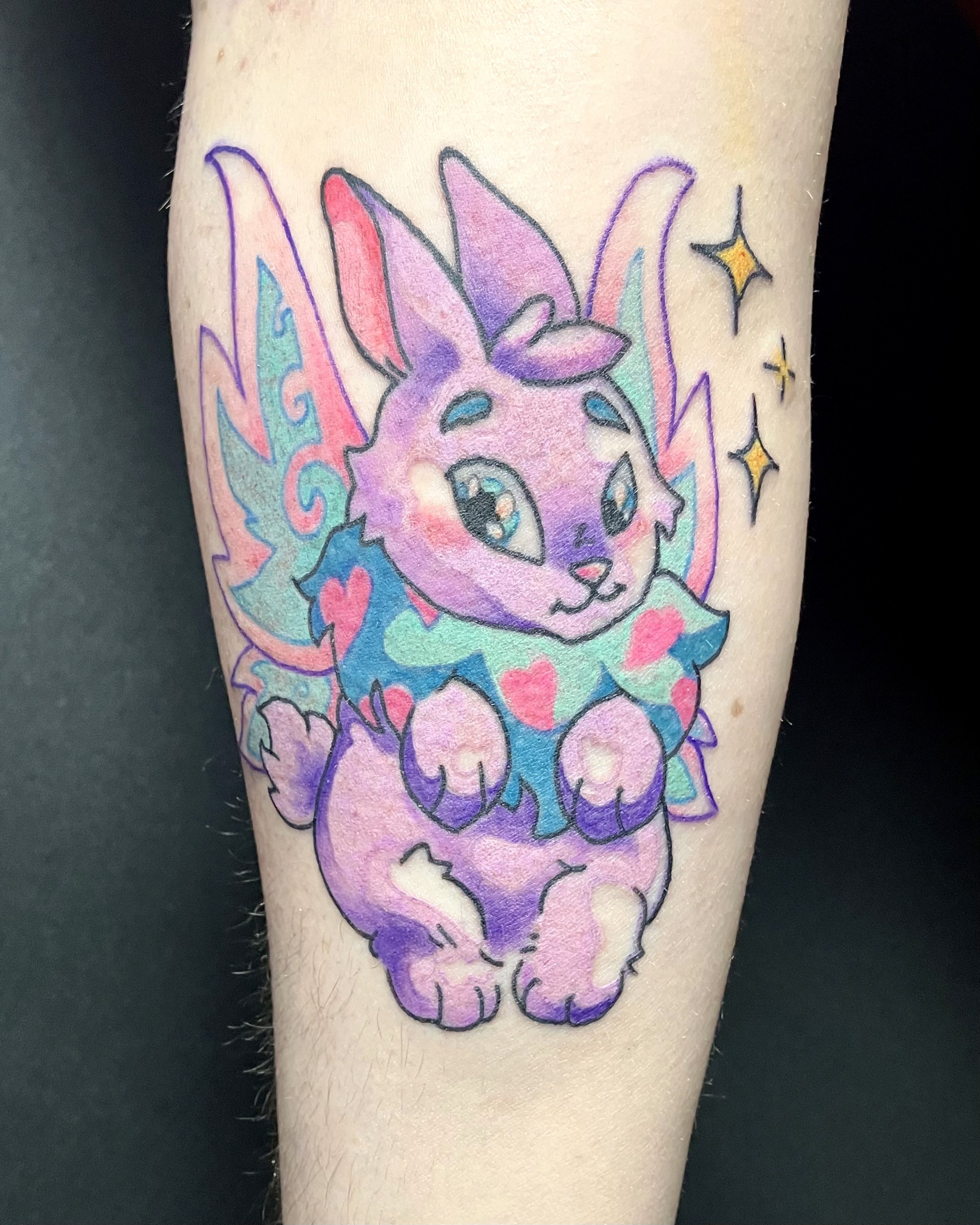 A vibrant tattoo of a chainsaw-like creature on a person's forearm. The tattoo is detailed with shades of orange, black, teal, and red.