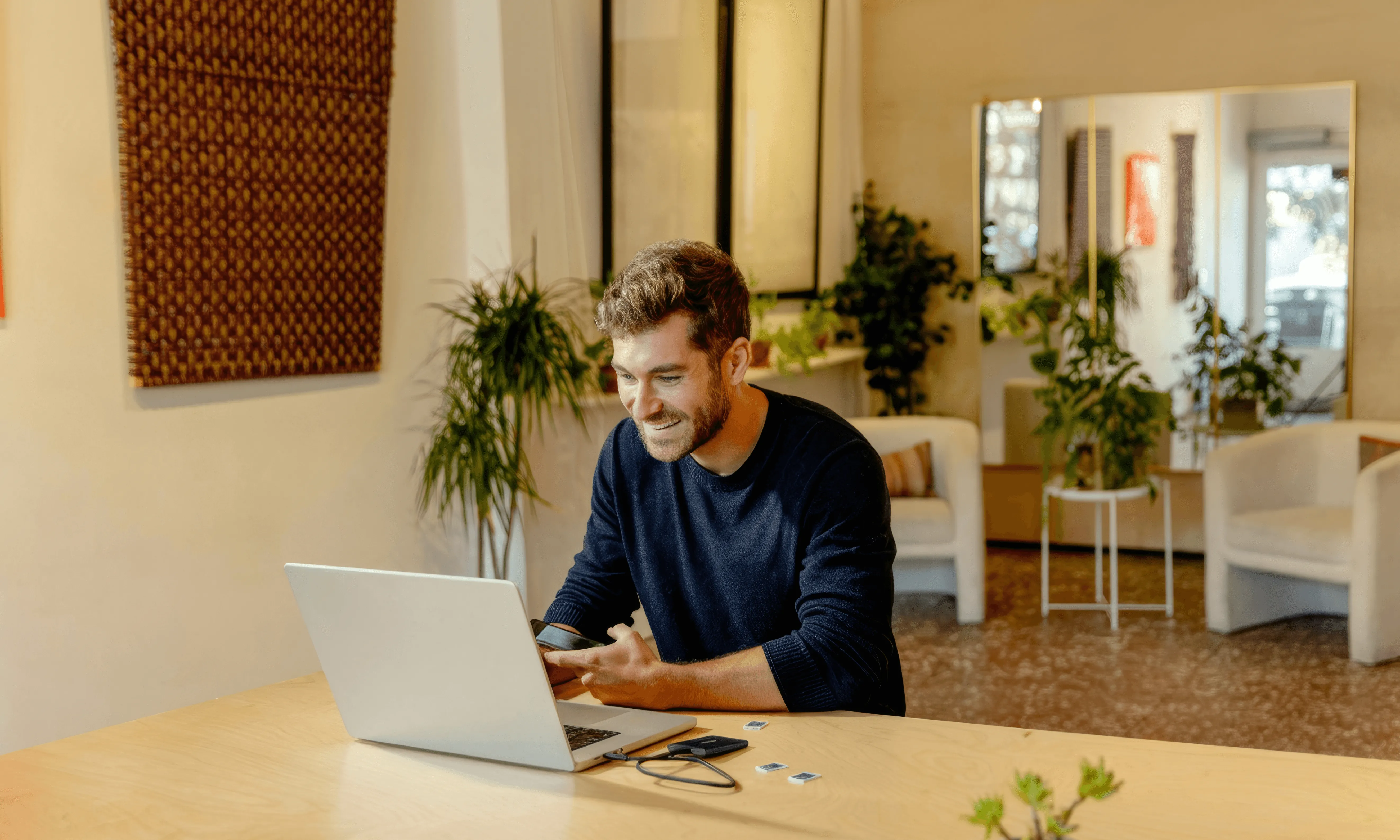 homme travaillant sur ordinateur portable dans espace coworking moderne avec plantes vertes