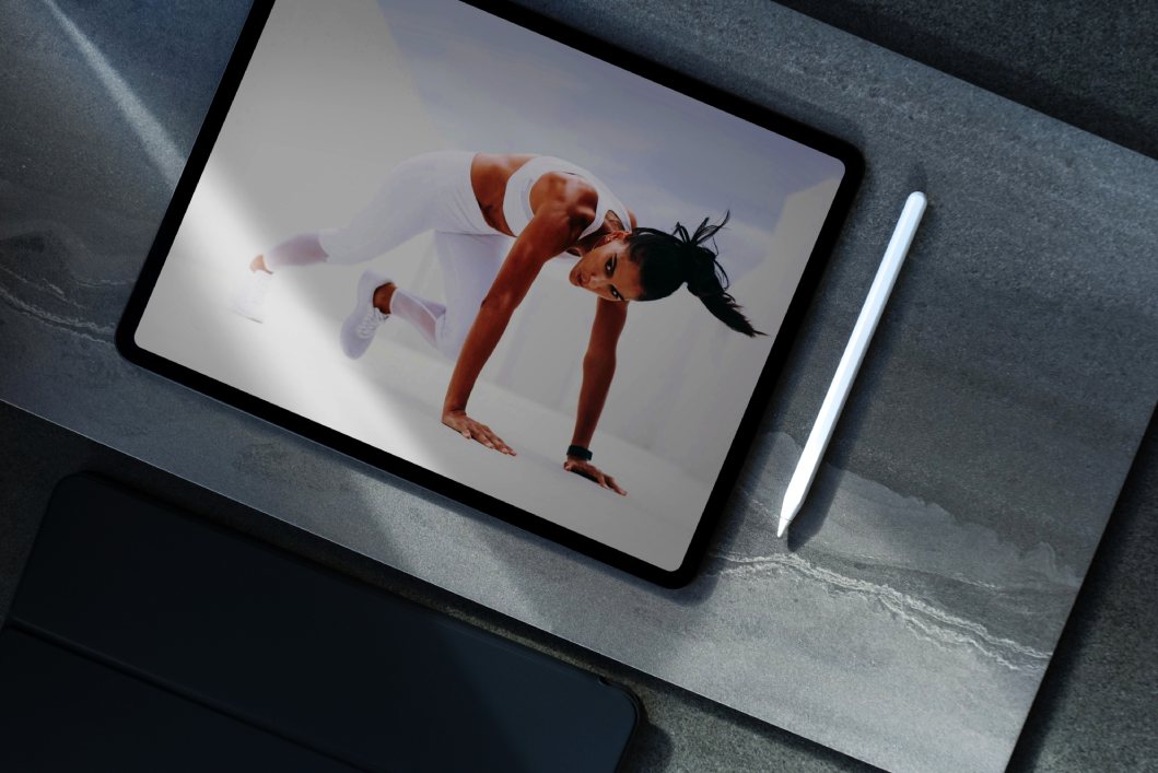 a tablet pc placed on a table with image of female doing pushups