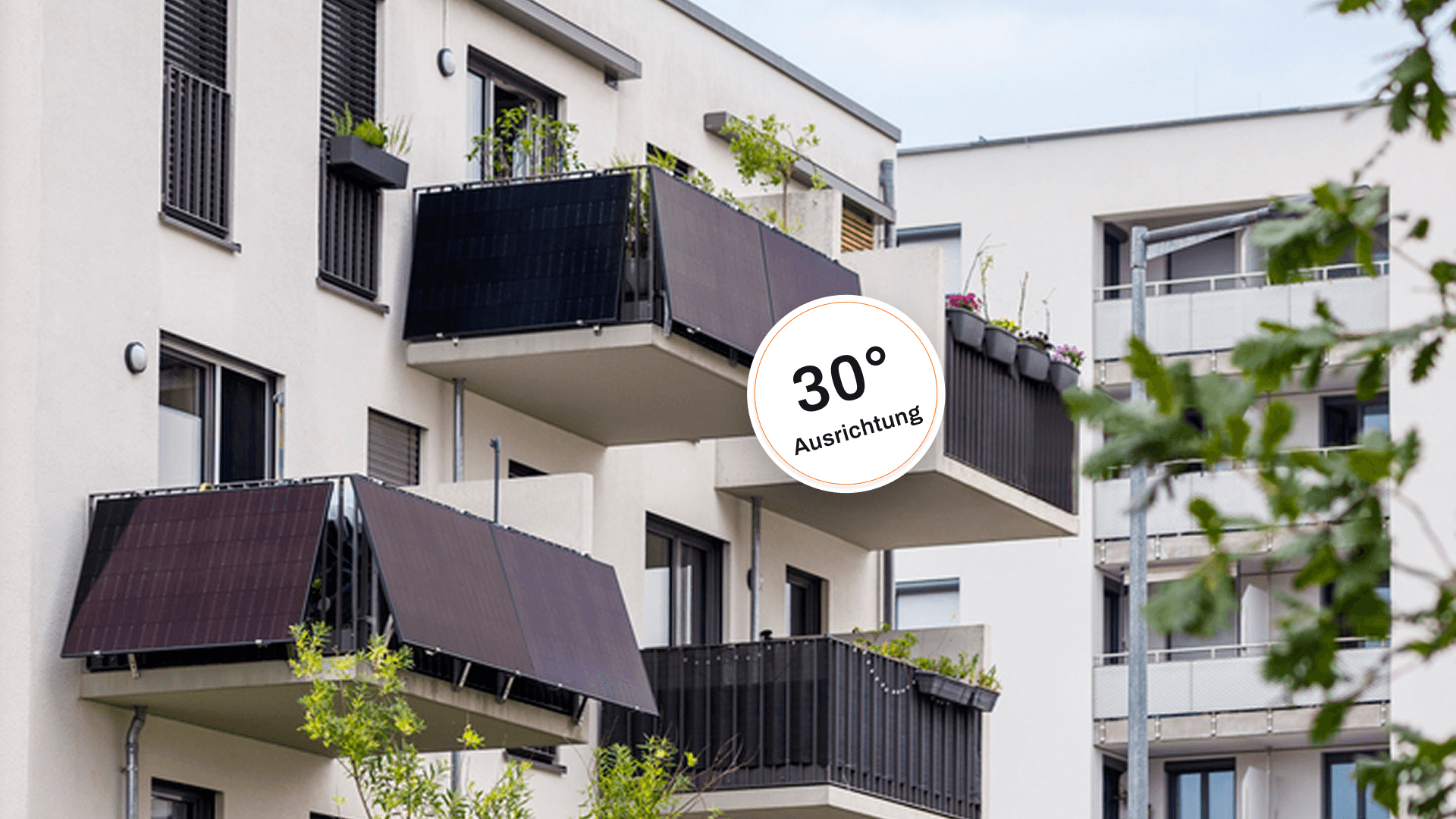 Modernes Wohngebäude mit mehreren Balkonen mit Photovoltaikmodulen und Grünflächen im Vordergrund.