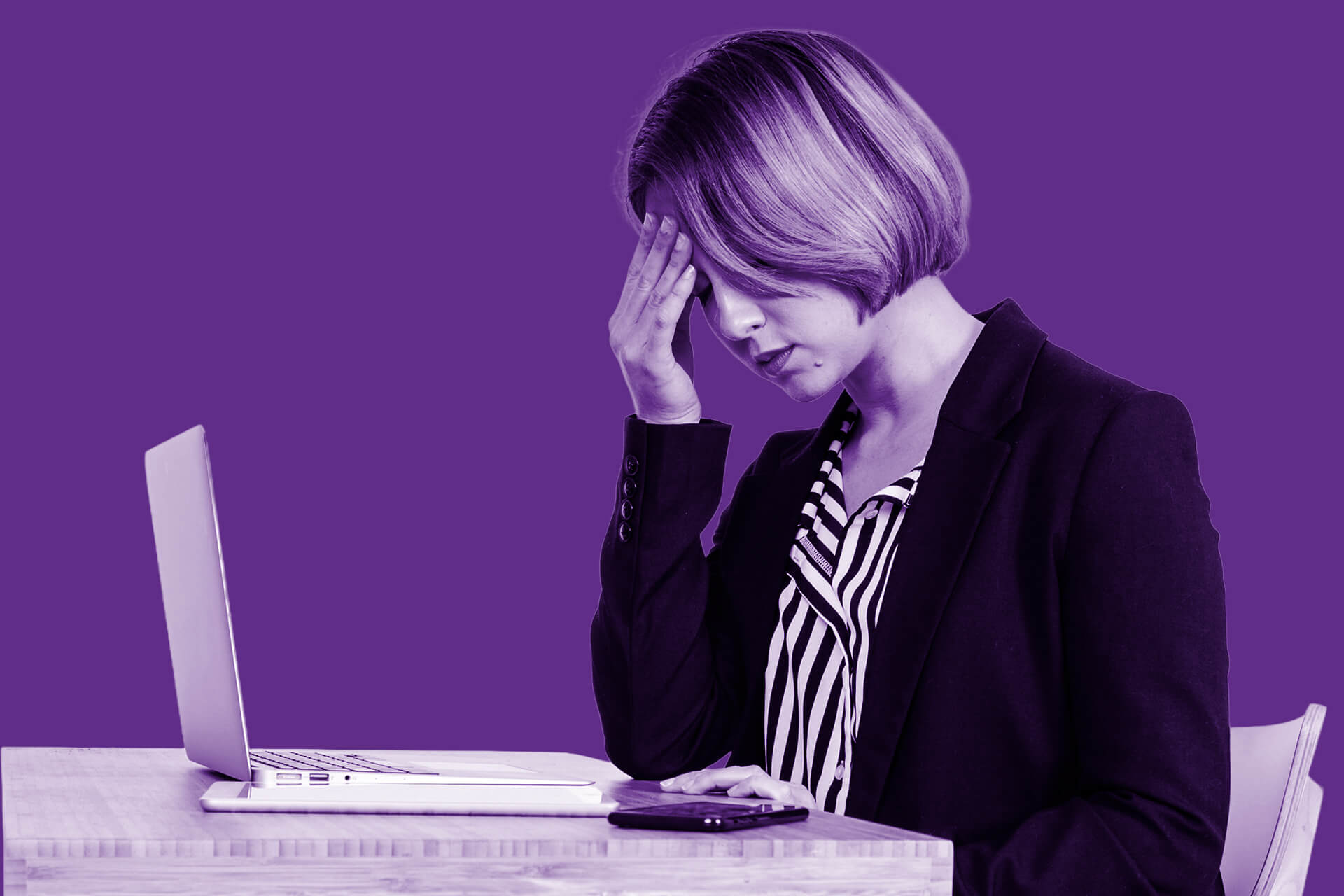 A woman sits looking at a laptop, head in hand, despairing at difficult design project