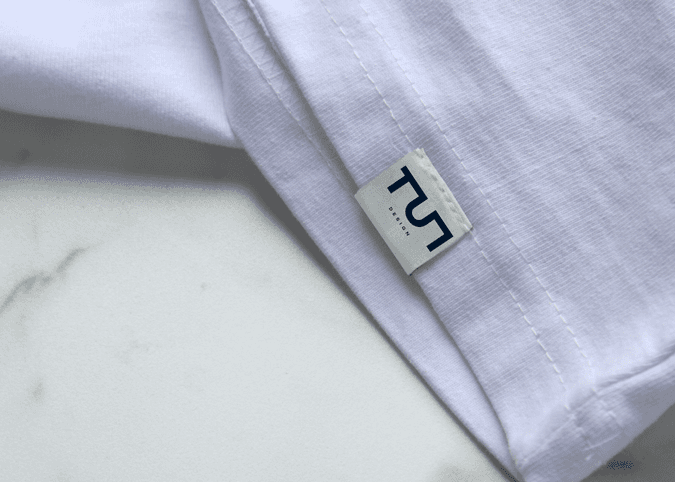 TUT Designs clothing label on white t-shirt showcasing modern Egyptian fashion branding with minimalist logo.