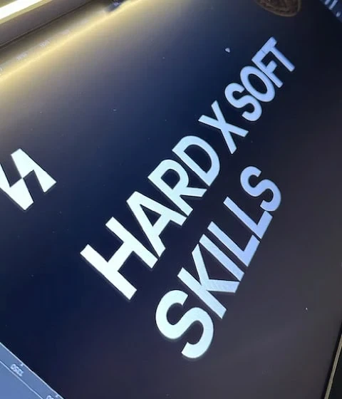 Placa exibindo "HARD X SOFT SKILLS" em letras em negrito sobre um fundo escuro.