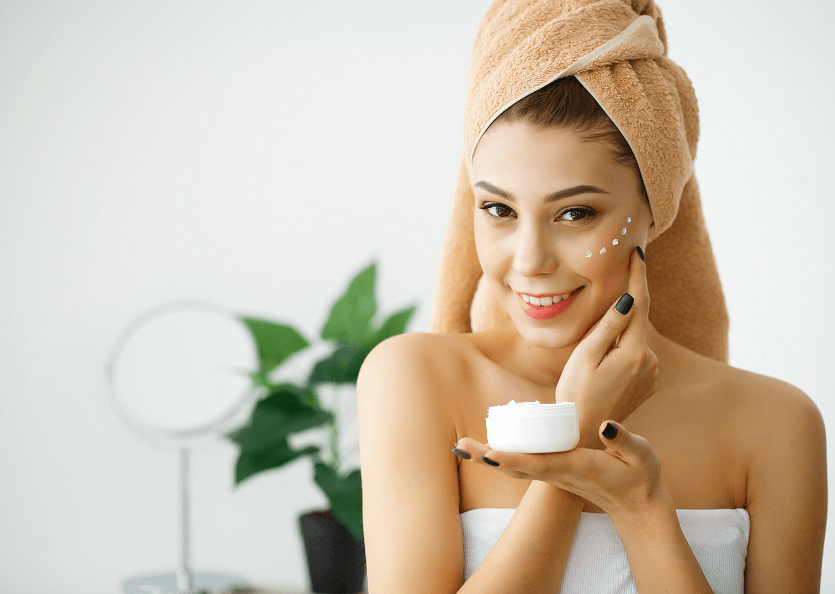 Woman applying cream from a white jar.