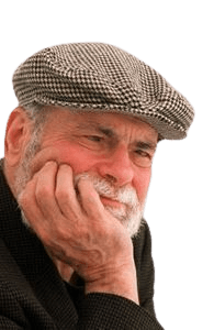 A candid color portrait of an elderly man with a white beard, resting his face on his hand and wearing a patterned flat cap and dark jacket. His expression appears thoughtful and relaxed, creating a warm, introspective atmosphere. The light background enhances focus on his face and gentle smile.