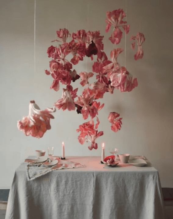 Instalación aérea de pétalos secos sobre mesa — obra floral poética de Irina Khatsernova inspirada en movimiento y ligereza.