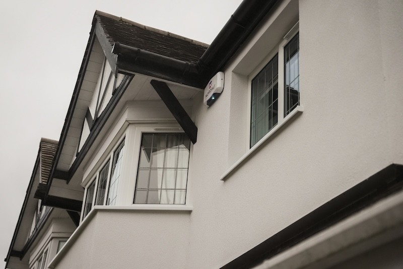 Top floor windows, wall and roof of a 1930s semi-detached home shot from below.