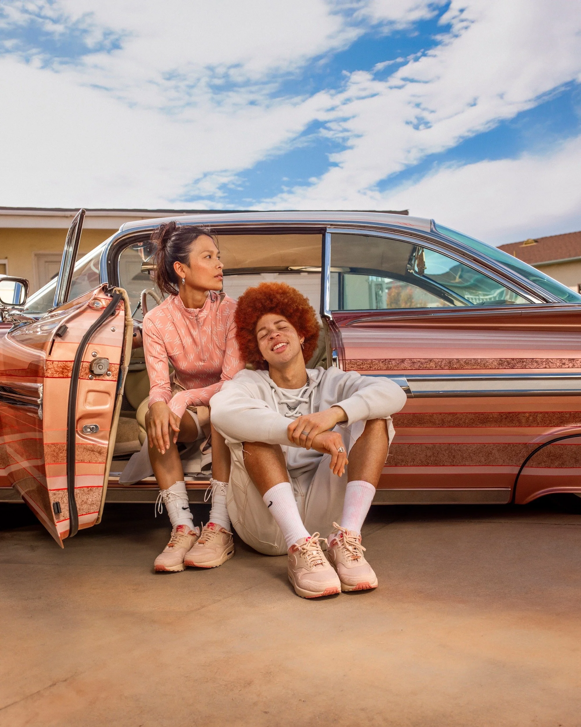 cinematic shot of models sitting by a car posing for a picture