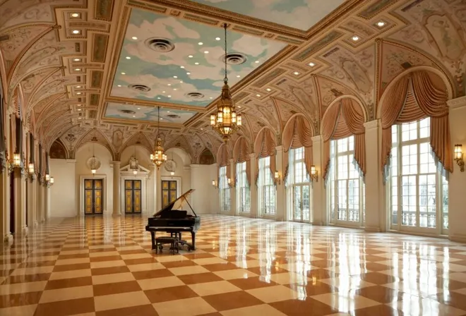 View of a Ballroom at The Breakers Hotel Palm Beach with a grand piano standing in the middle.