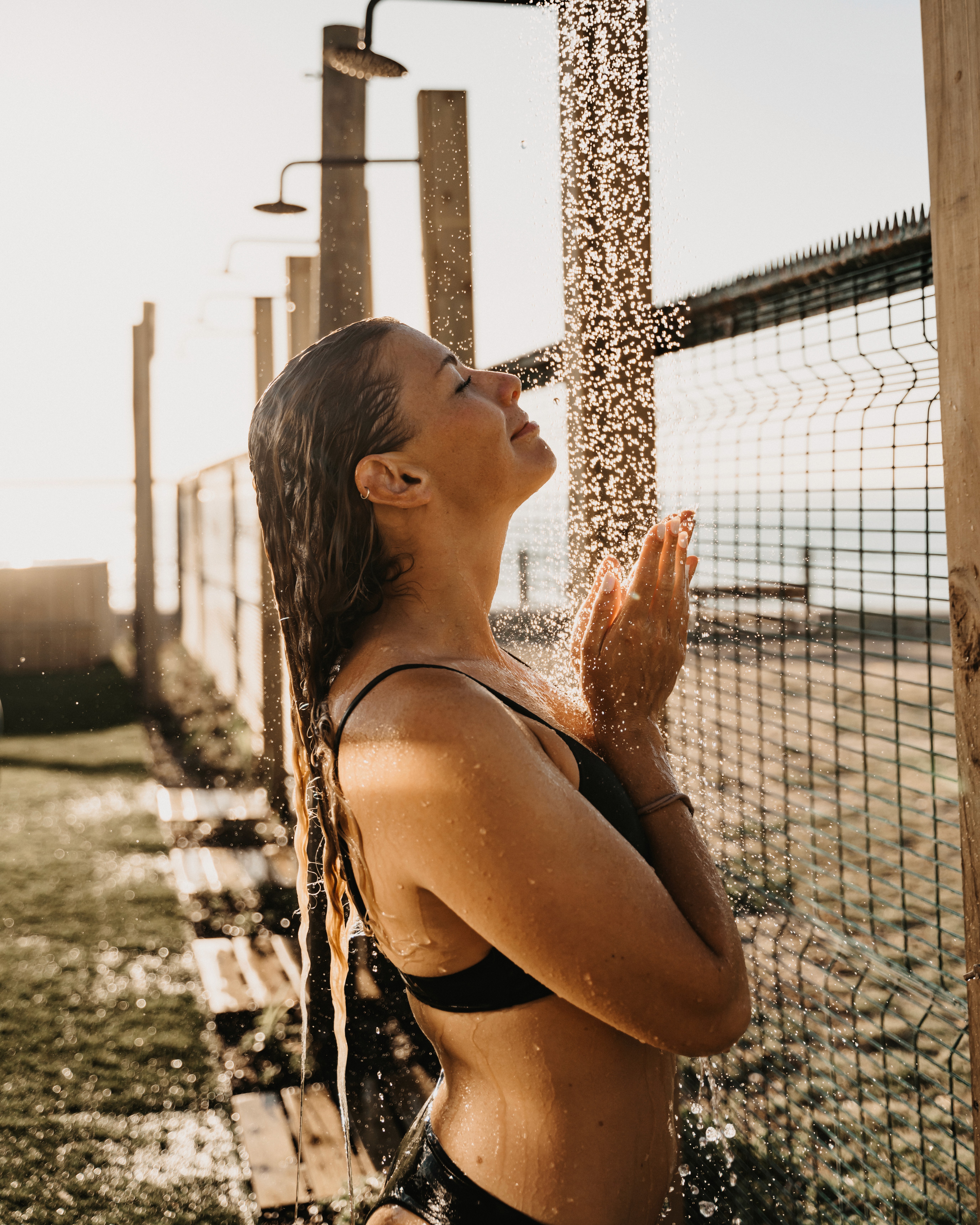 Woman rinsing off under the outdoor shower at SaunaHaüs Cape Town during a sauna and ice bath wellness ritual.