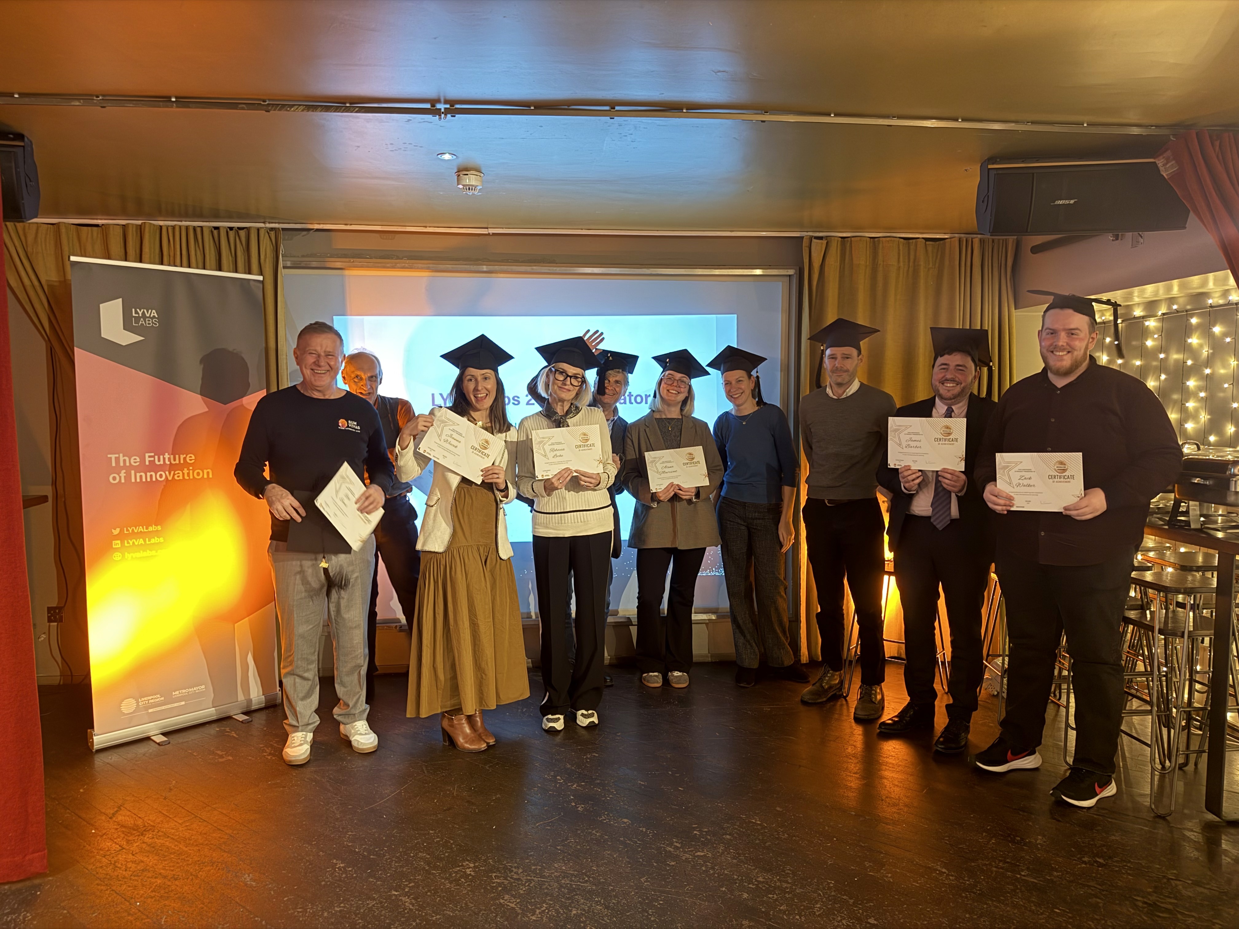 LYVA Labs cohort wearing mortarboards ion a stage