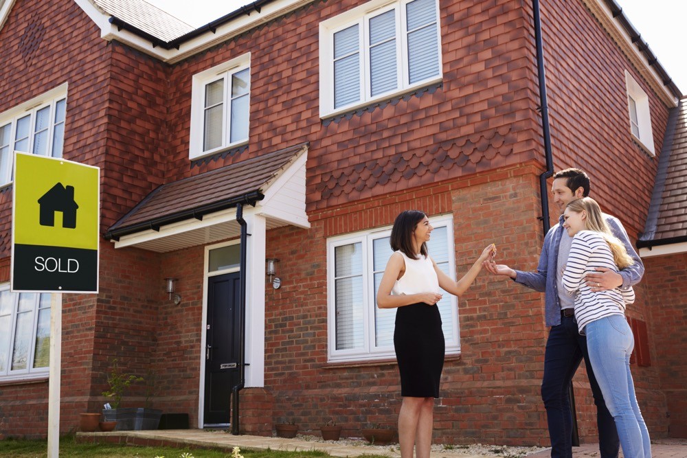 young-couple-collecting-keys-to-new-home-from-real