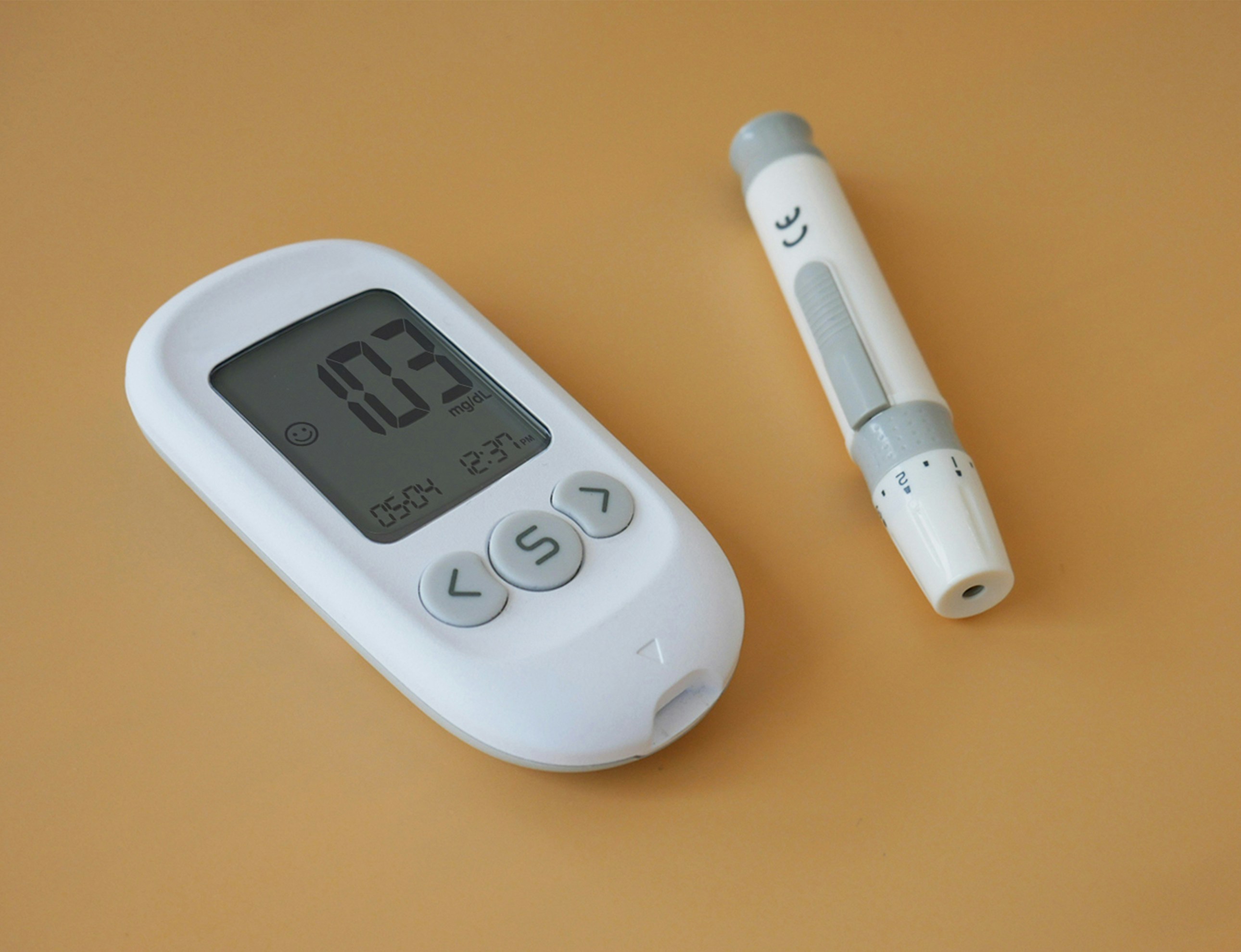 a glucose monitor and finger prick test device on a table