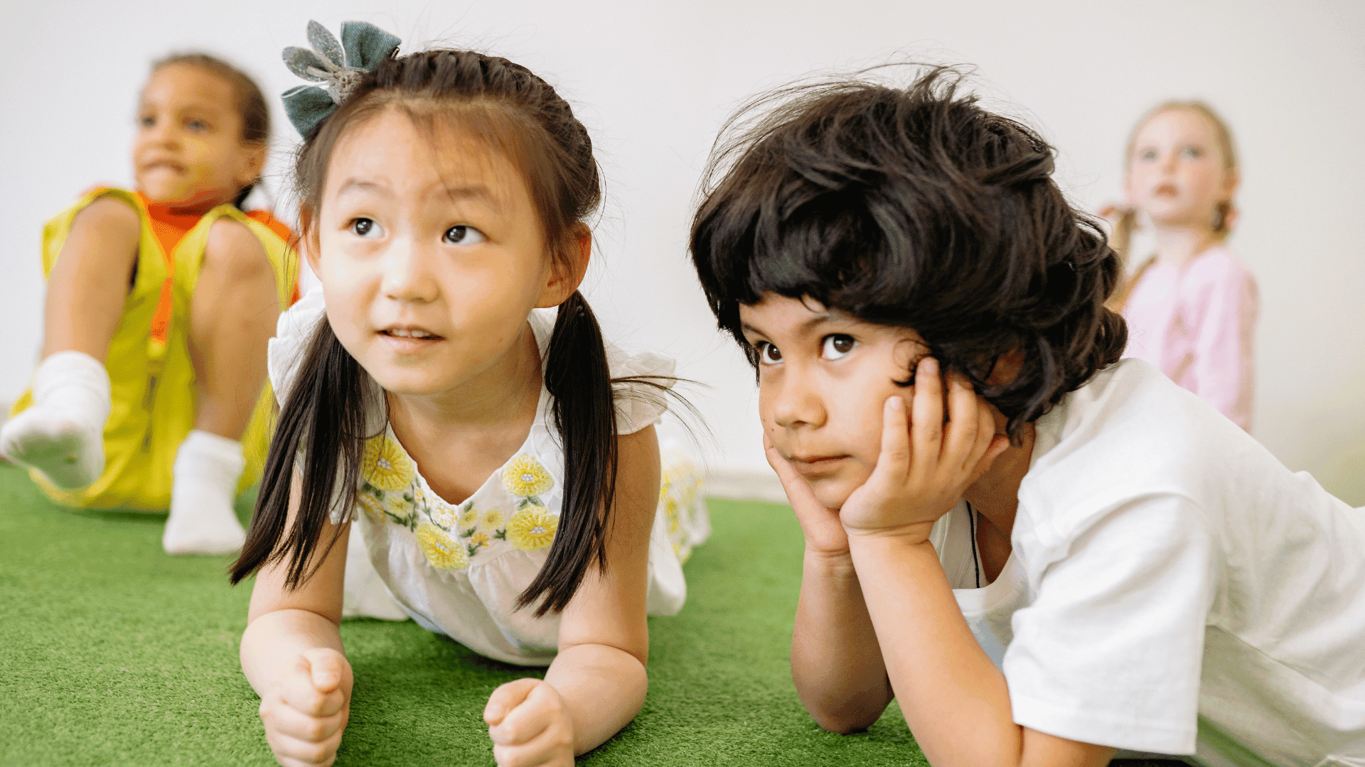 Four children sitting on the floor, looking calm and focused on something in front of them.