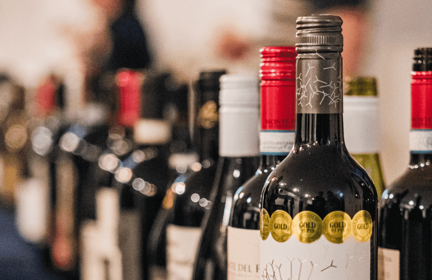 Some bottles of wine on a table with some red glasses.