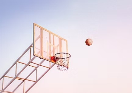Ein Basketball fliegt auf einen Korb im Freien zu – Sportförderung des ESV Staffelse Basketball e.V. durch die DAG.