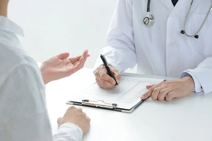 AI in healthcare enabling smoother consultations as a doctor fills out a patient chart while speaking with a patient.