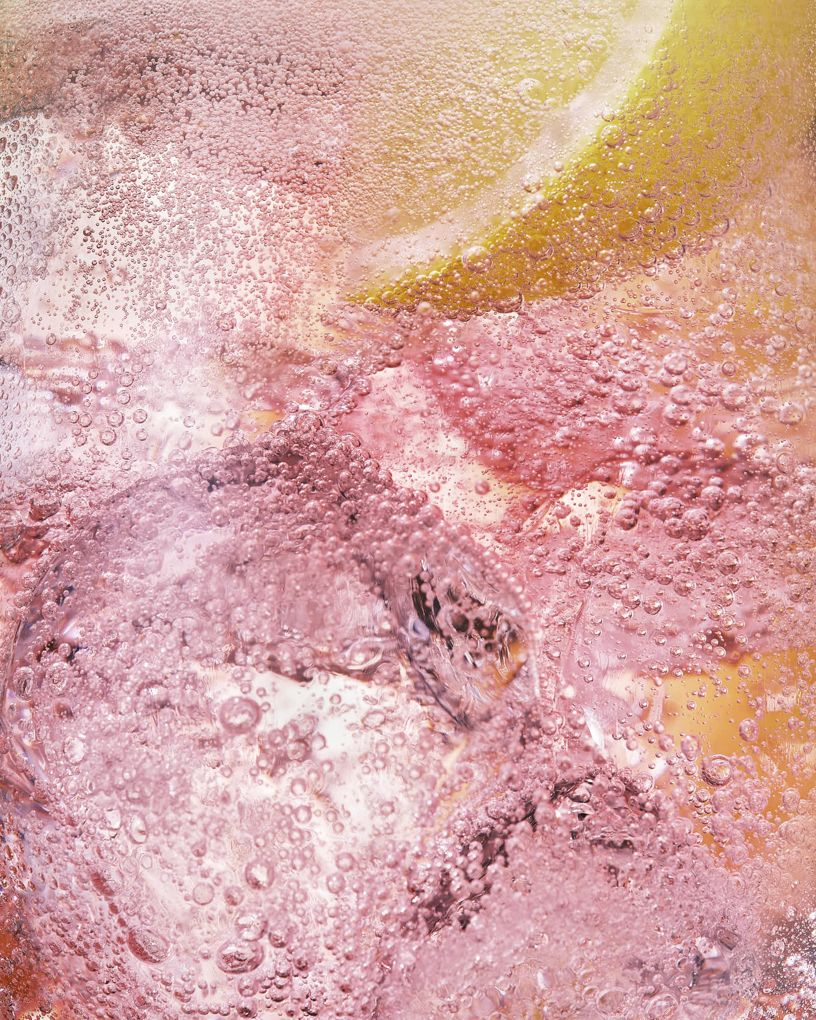 Close-up of pink ice drink with a hint of lemon, showcasing bubbly textures and refreshing colors.