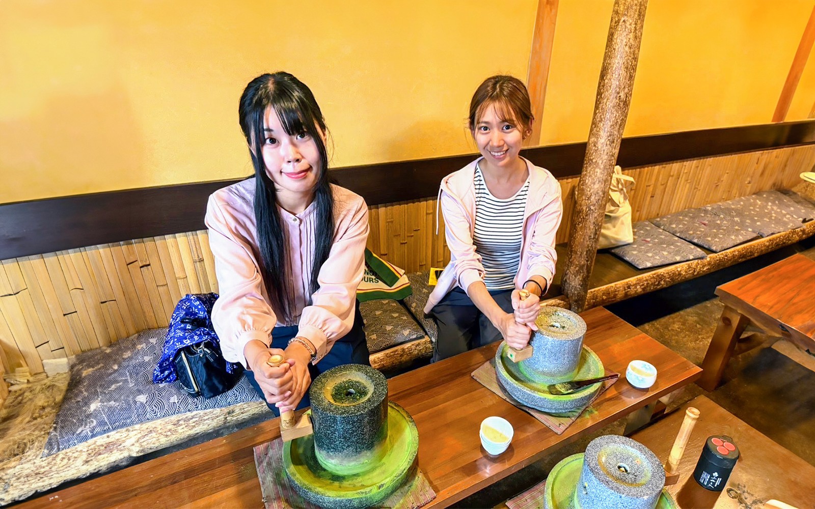 Visitantes moliendo té matcha en un taller tradicional en el tour en autobús de un día por Nara y Kioto.