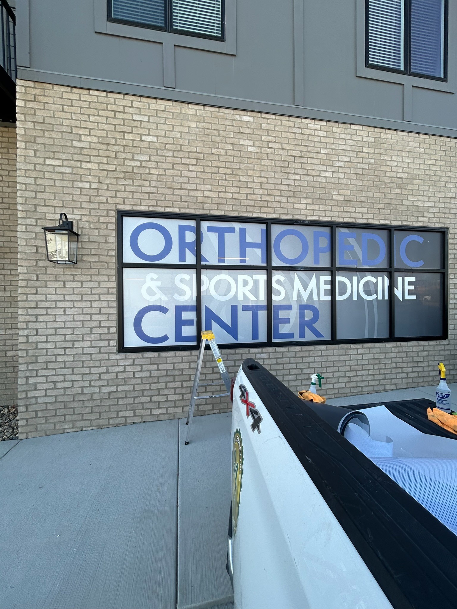OSMC Orthopedic and Sports Medicine Center window signage being installed at the St. Joseph Missouri practice location