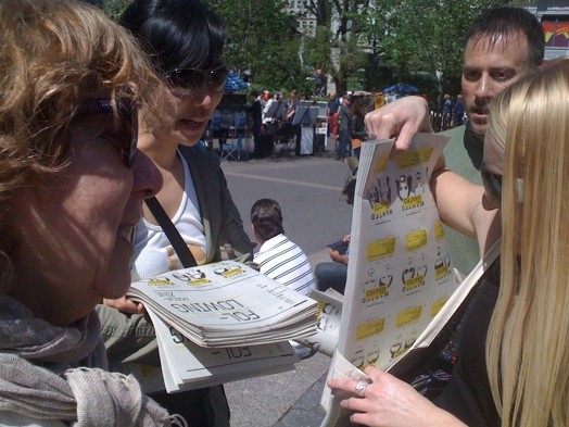 A photo of a group of people distributing flyers on the street.