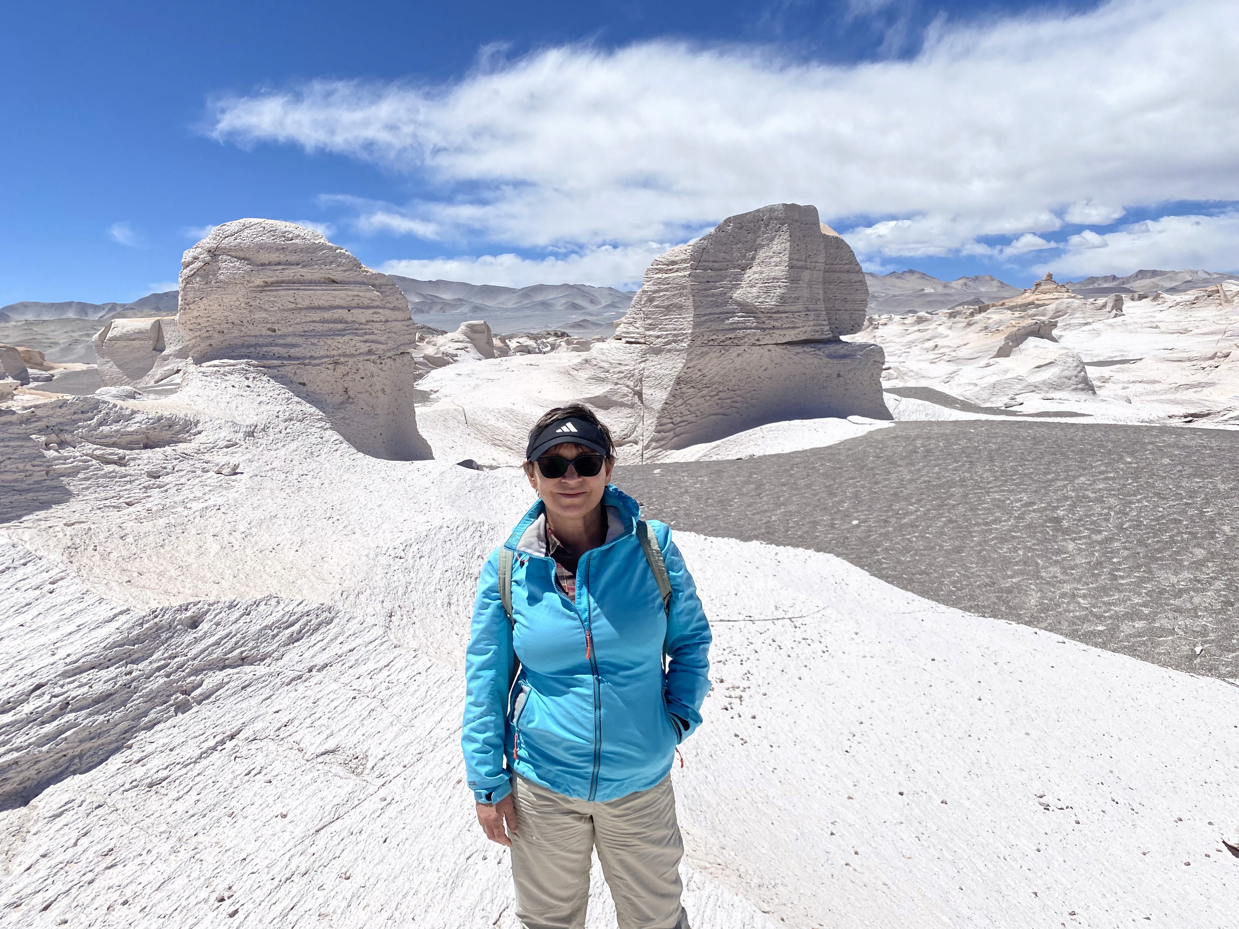 Mujer sentada sobre un tronco frente a una cascada doble en un bosque frondoso de Argentina.