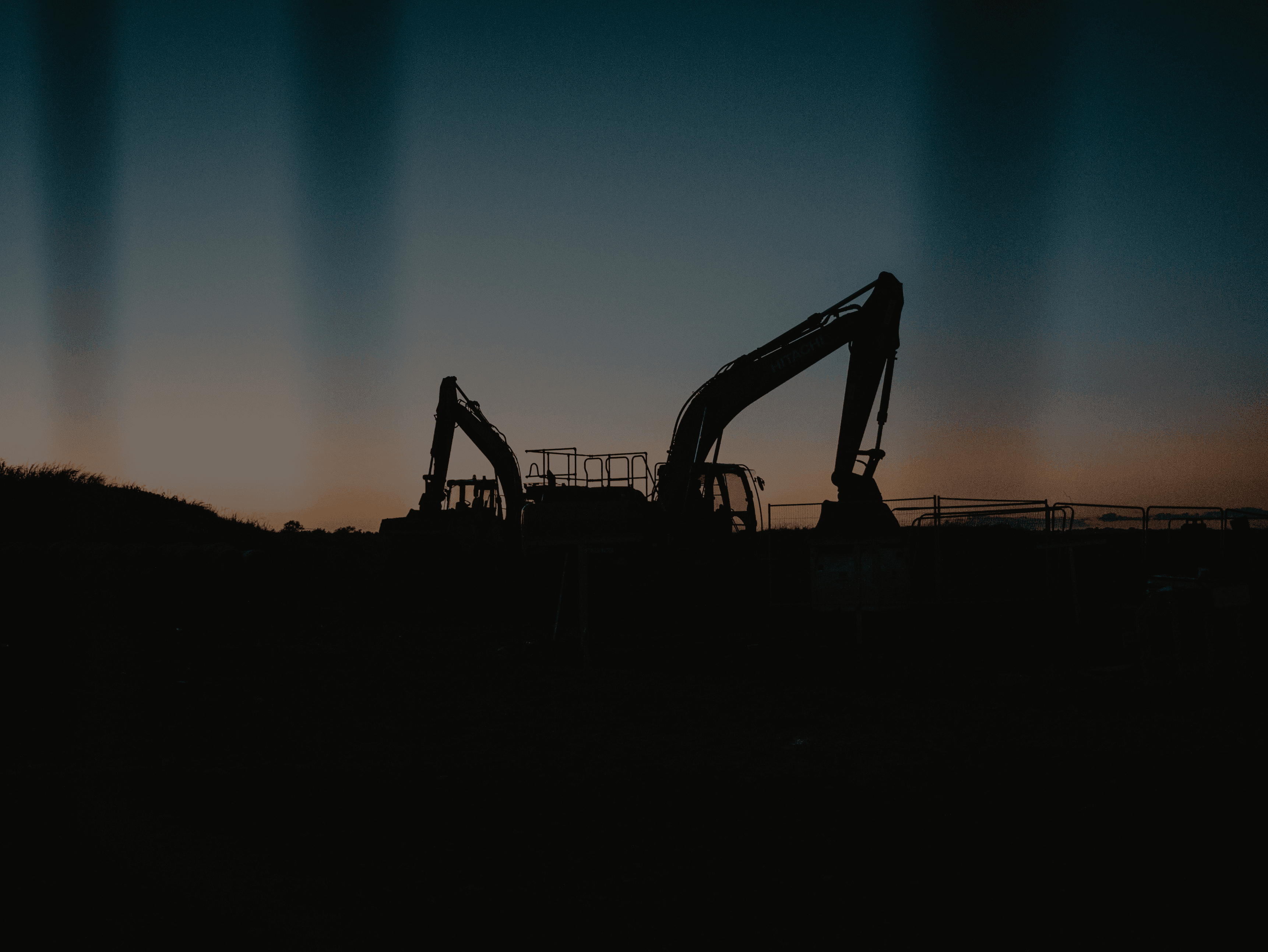 an excavator is silhouetted against a sunset