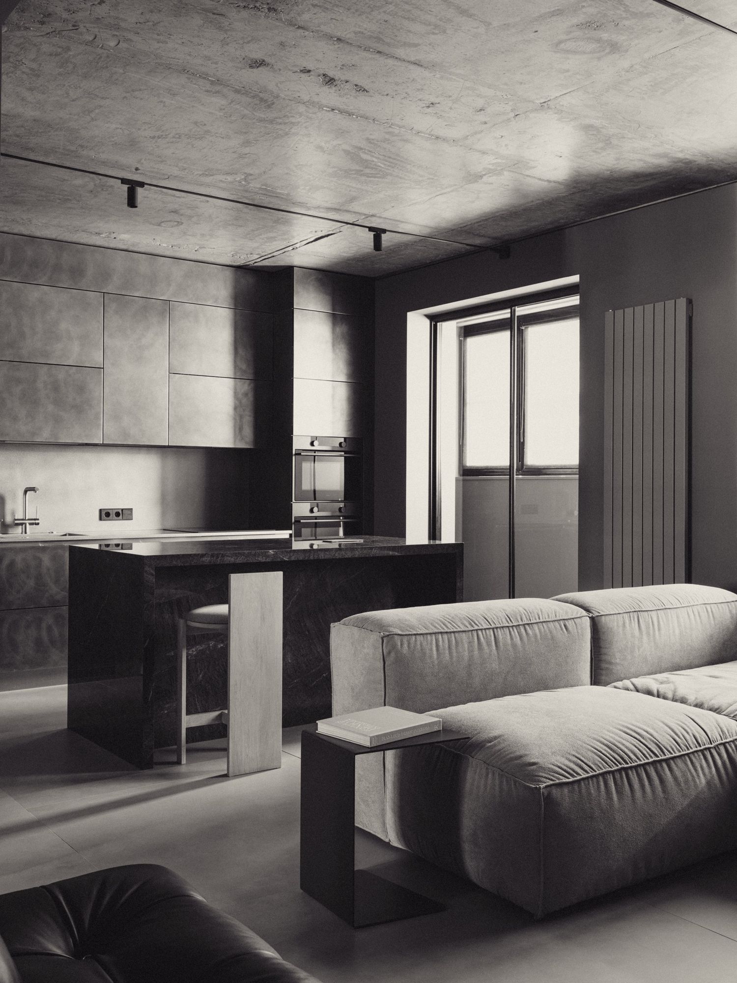An open kitchen with concrete walls and a pale sofa