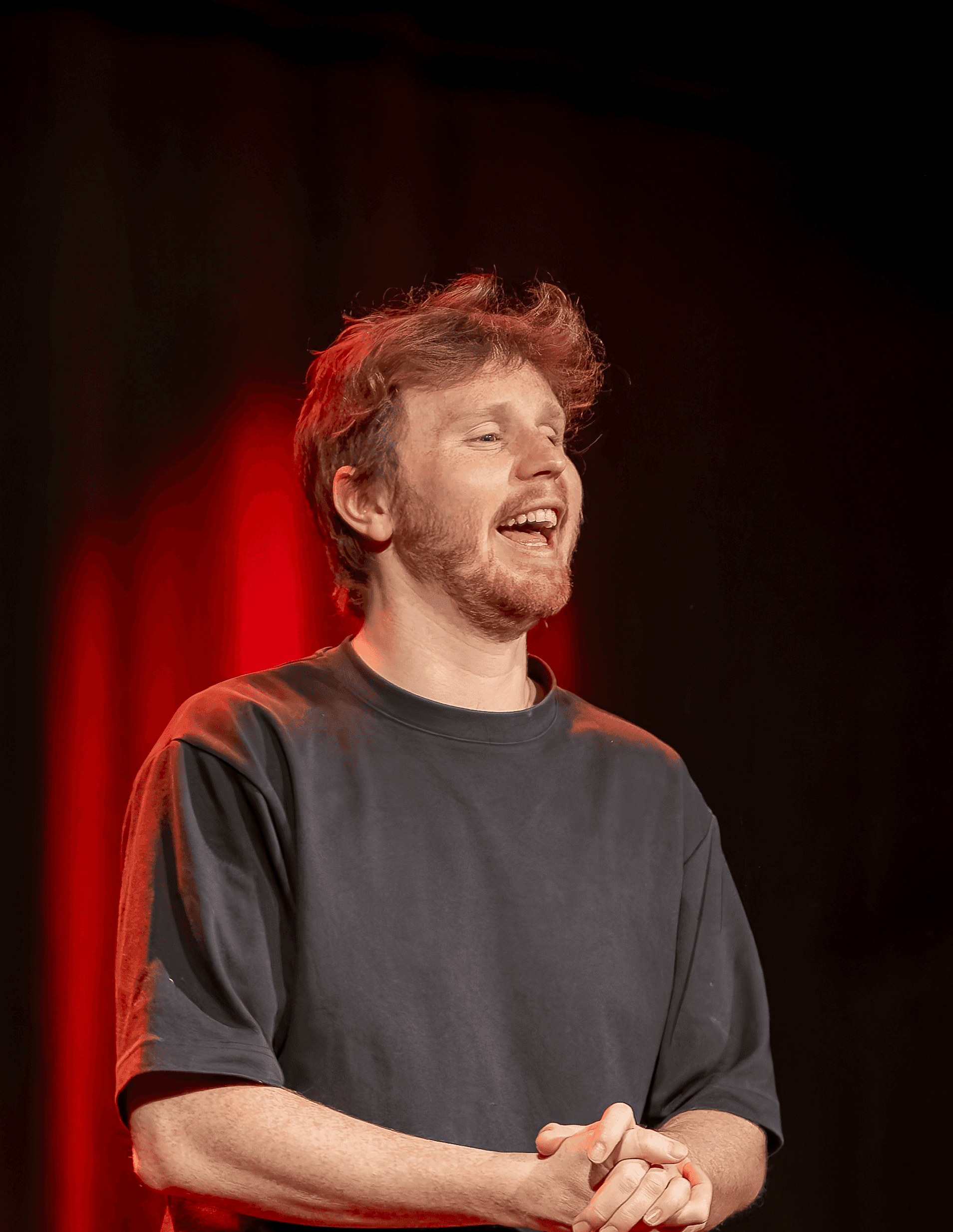 Jojo bernard sourit sur scène devant un rideau de spectacle