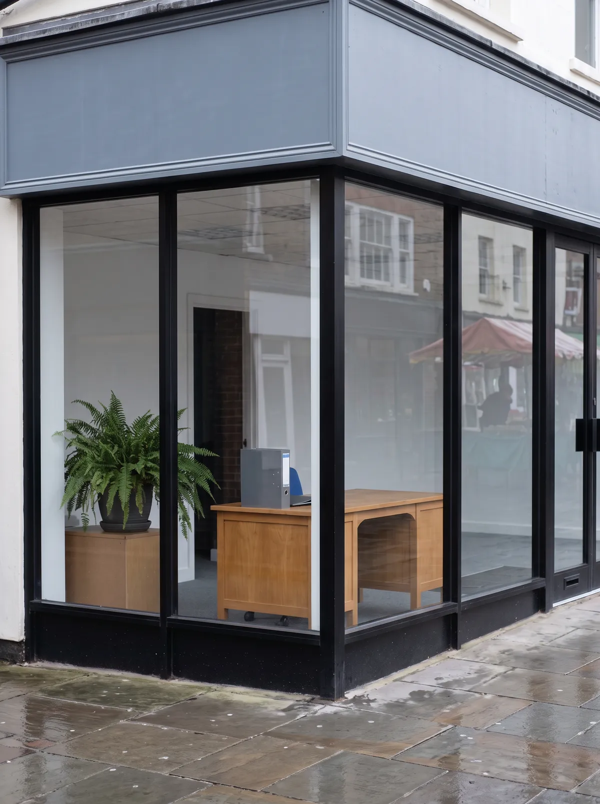 The glazed front door of the Kingston office with a plant and an oak desk visible inside