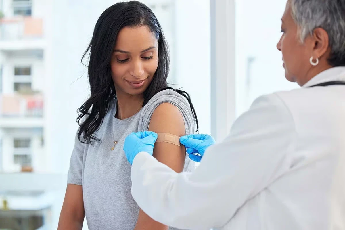Healthcare worker giving a vaccine injection into a woman’s upper arm