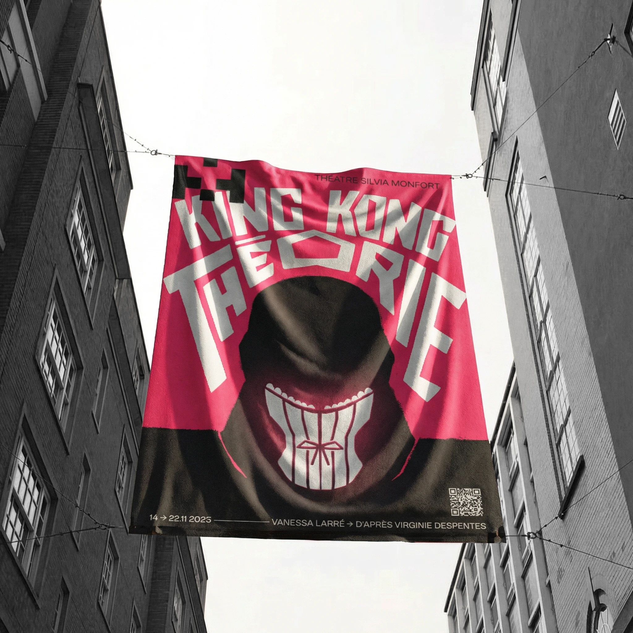 Street banner showing the King Kong Théorie theatre poster suspended between buildings, with distorted white lettering, a bright pink and black background, and a dark figure wearing a corset.