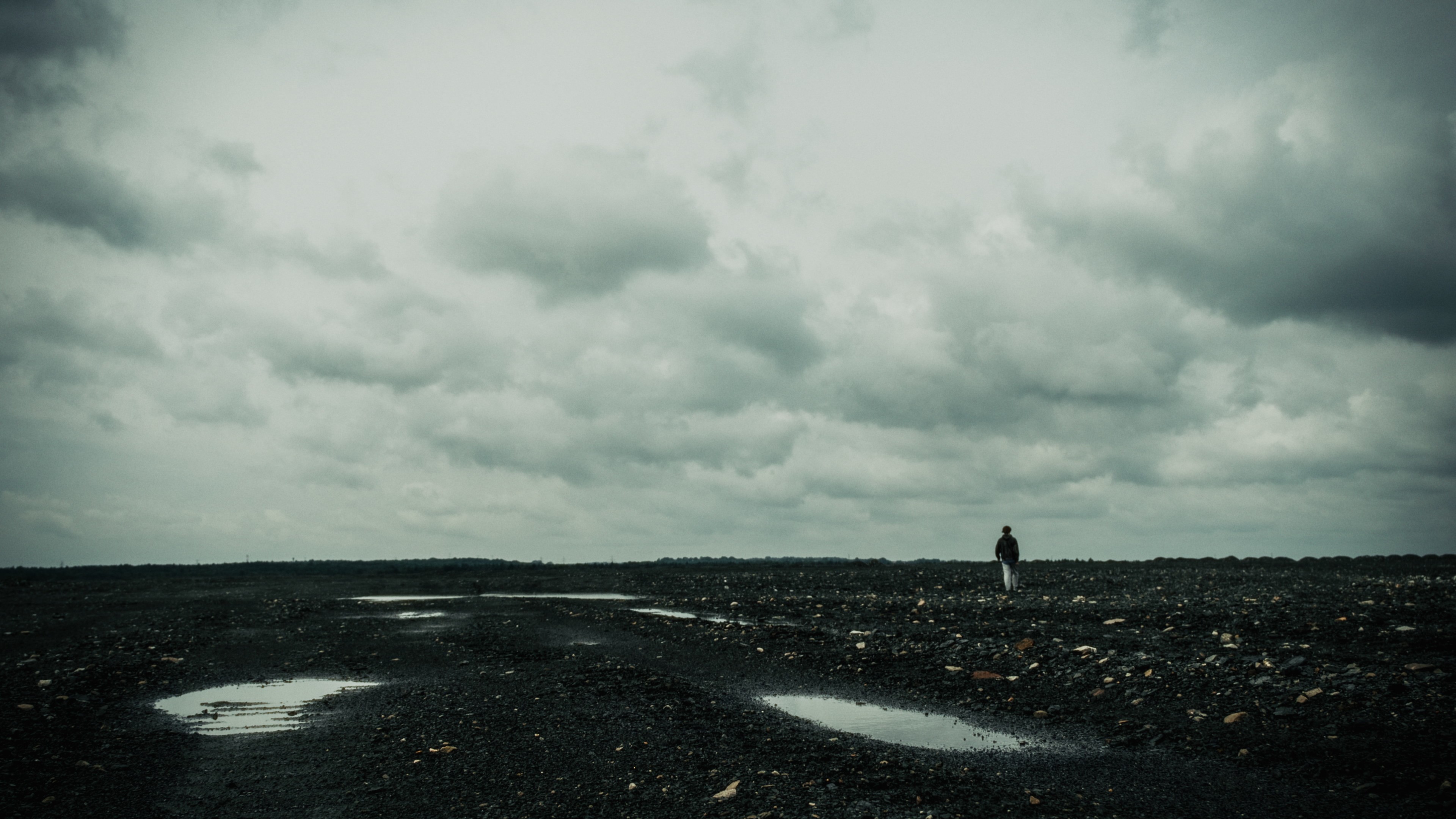Wide shot of a lone figure standing on a desolate mining heap in Silesia.