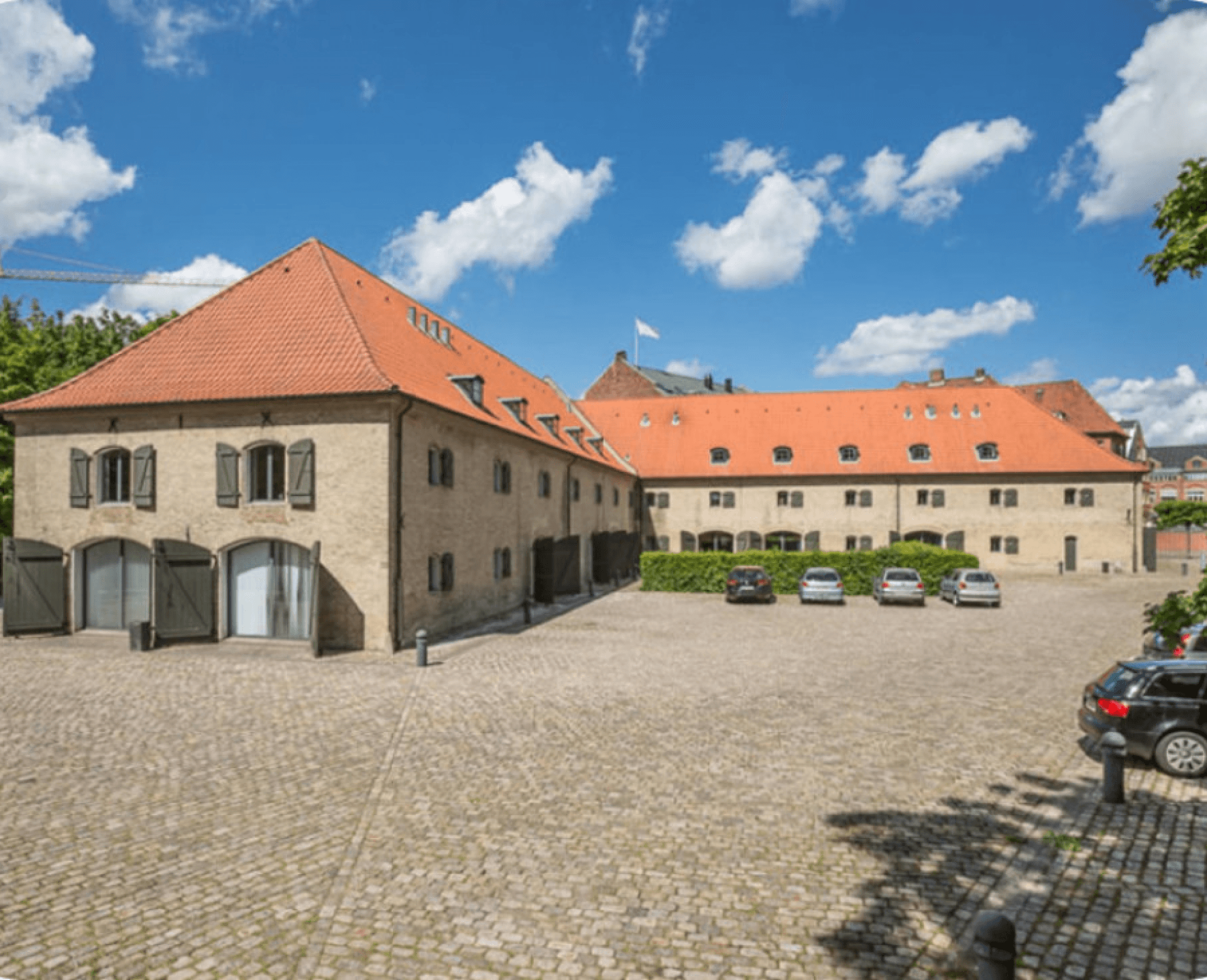 The exterior of the Copenhagen office from a distance, light beige brick walls and an orange roof.